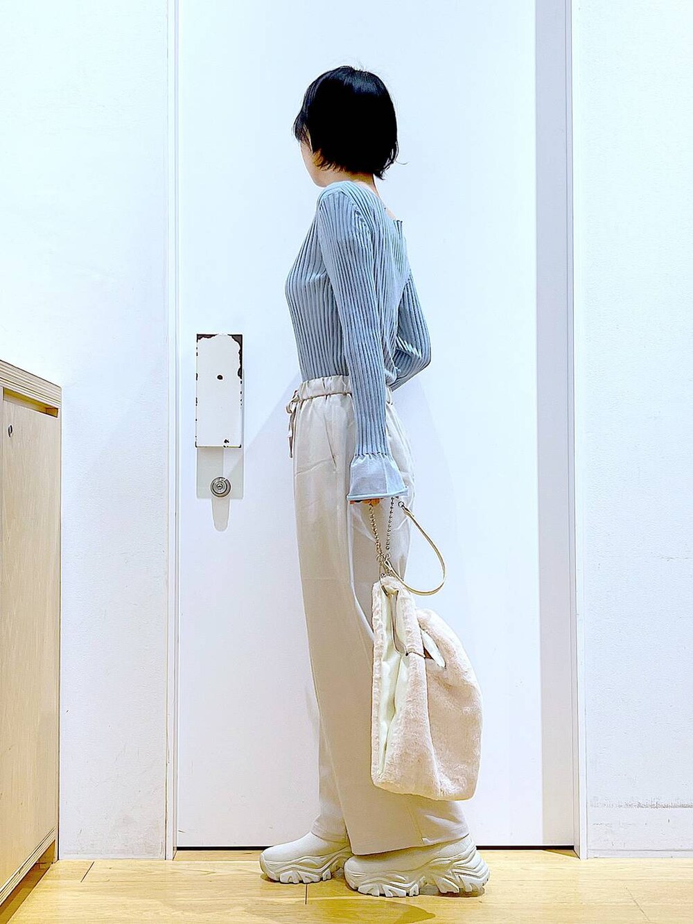 ブルー系のニット/セーター、ホワイト系のショルダーバッグ、ベージュ系のブーツを着用したレディースの冬コーディネートの3枚目の写真