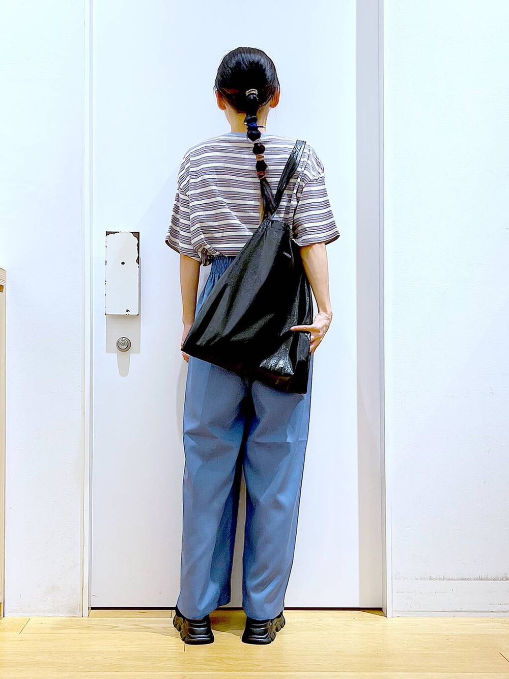 ブラック系のトートバッグ、ブラック系のサンダル、ベージュ系のTシャツ/カットソーを着用したレディースの夏コーディネートの5枚目の写真