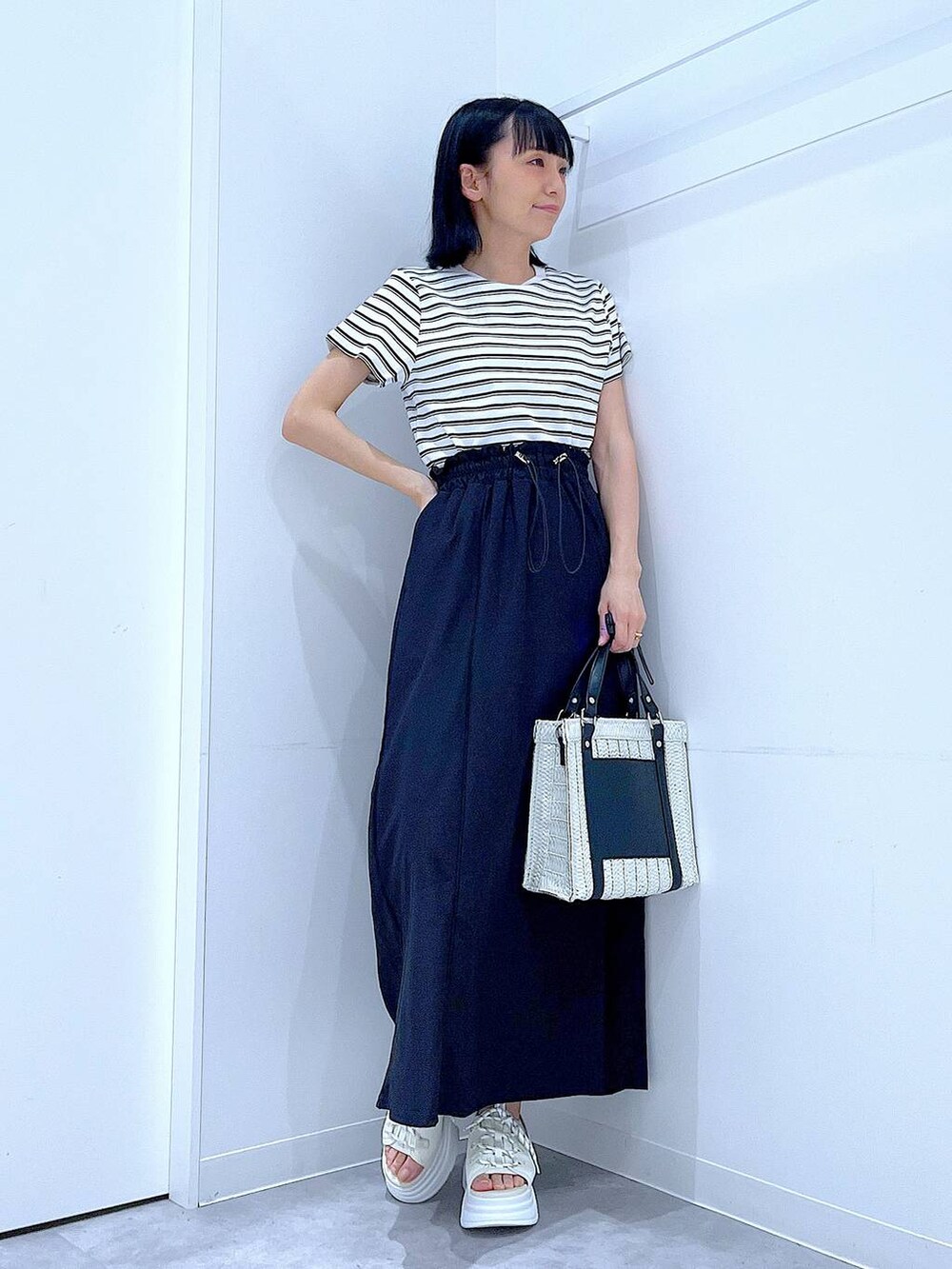 ホワイト系のショルダーバッグ、ホワイト系のサンダル、ベージュ系のTシャツ/カットソーを着用したレディースの夏コーディネートの2枚目の写真