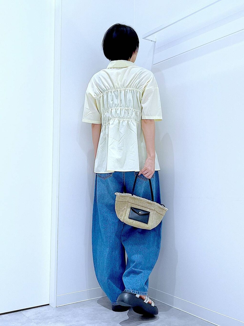 ブルー系のデニムパンツ、ベージュ系のショルダーバッグ、シルバー系のサンダルを着用したレディースの夏コーディネートの5枚目の写真