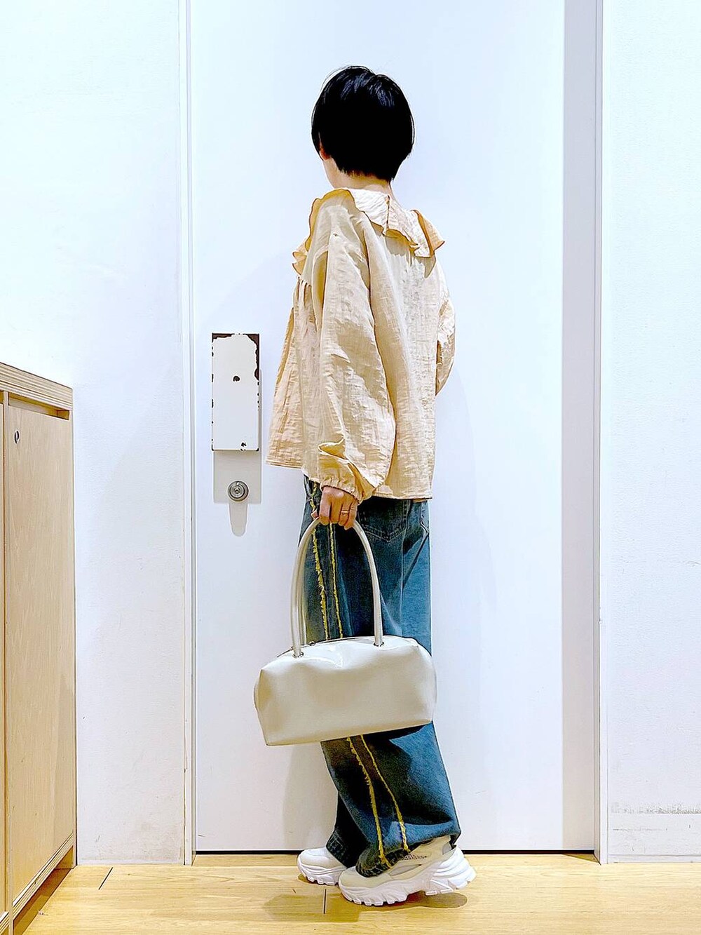 ホワイト系のボストンバッグ、ホワイト系のスニーカー、ブルー系のデニムパンツを着用したレディースの春コーディネートの3枚目の写真
