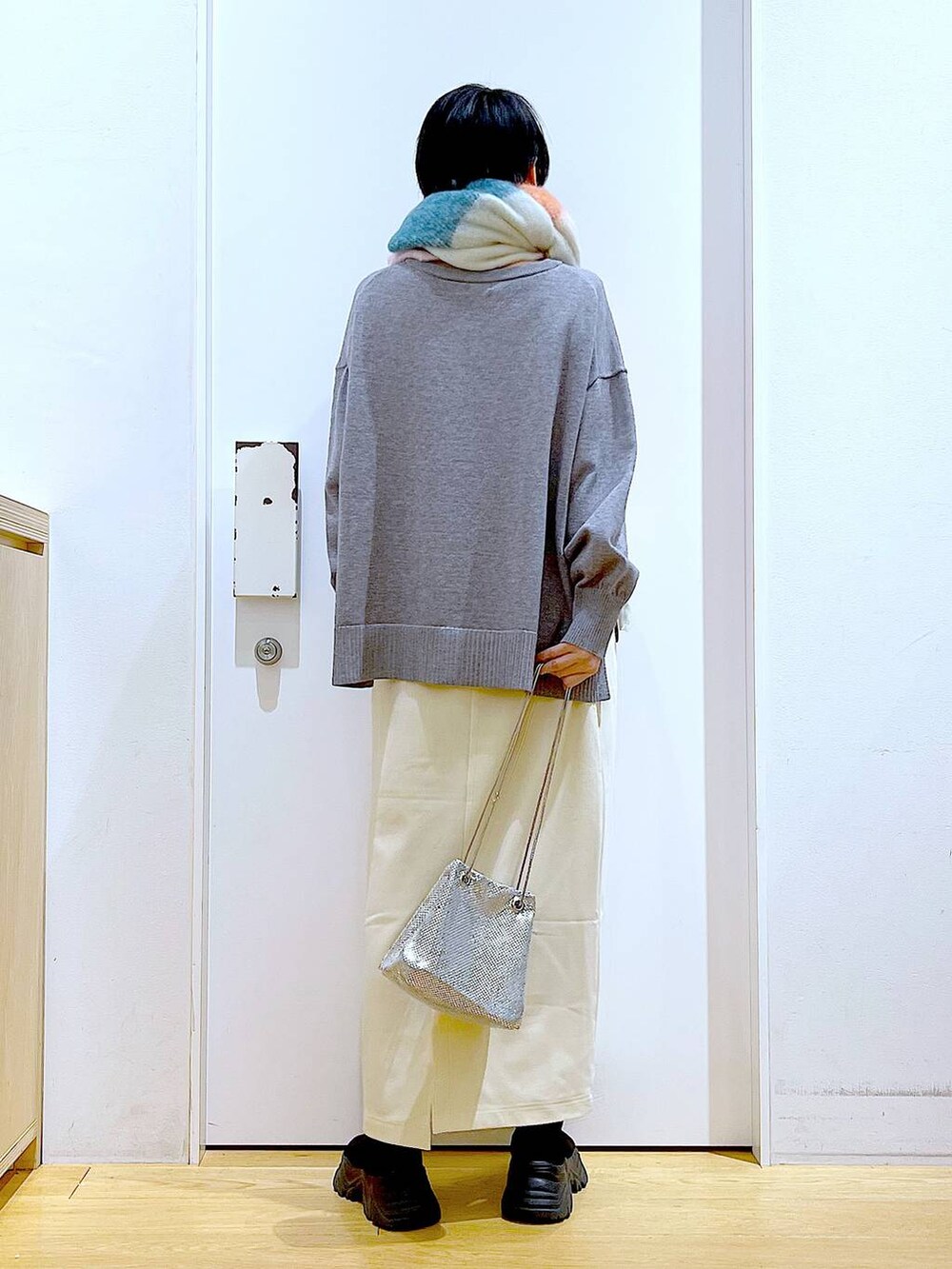 ブラック系のブーツ、ホワイト系のスカート、グレー系のニット/セーターを着用したレディースの冬コーディネートの5枚目の写真