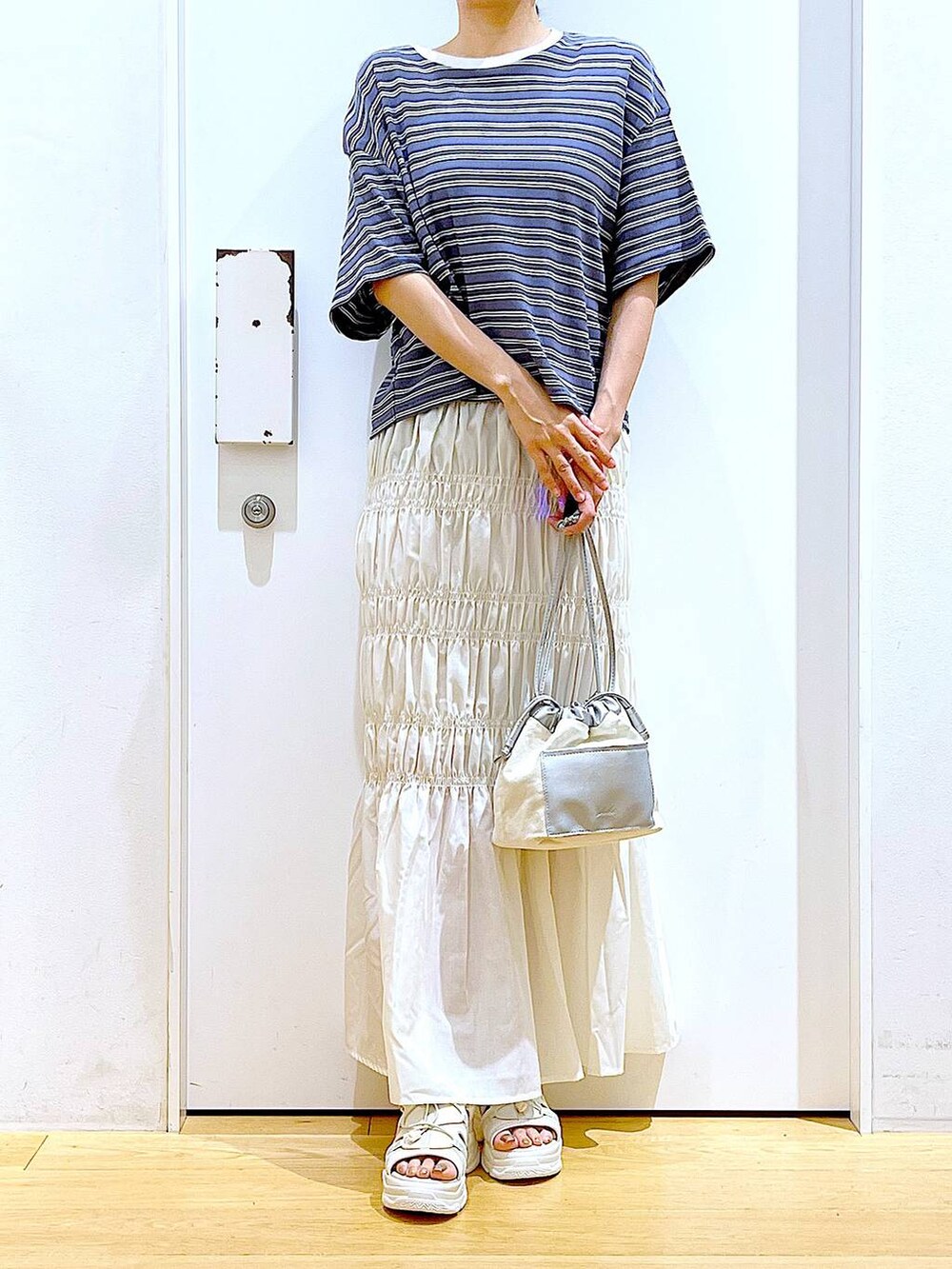 ホワイト系のショルダーバッグ、ホワイト系のサンダル、グレー系のTシャツ/カットソーを着用したレディースの夏コーディネートの6枚目の写真