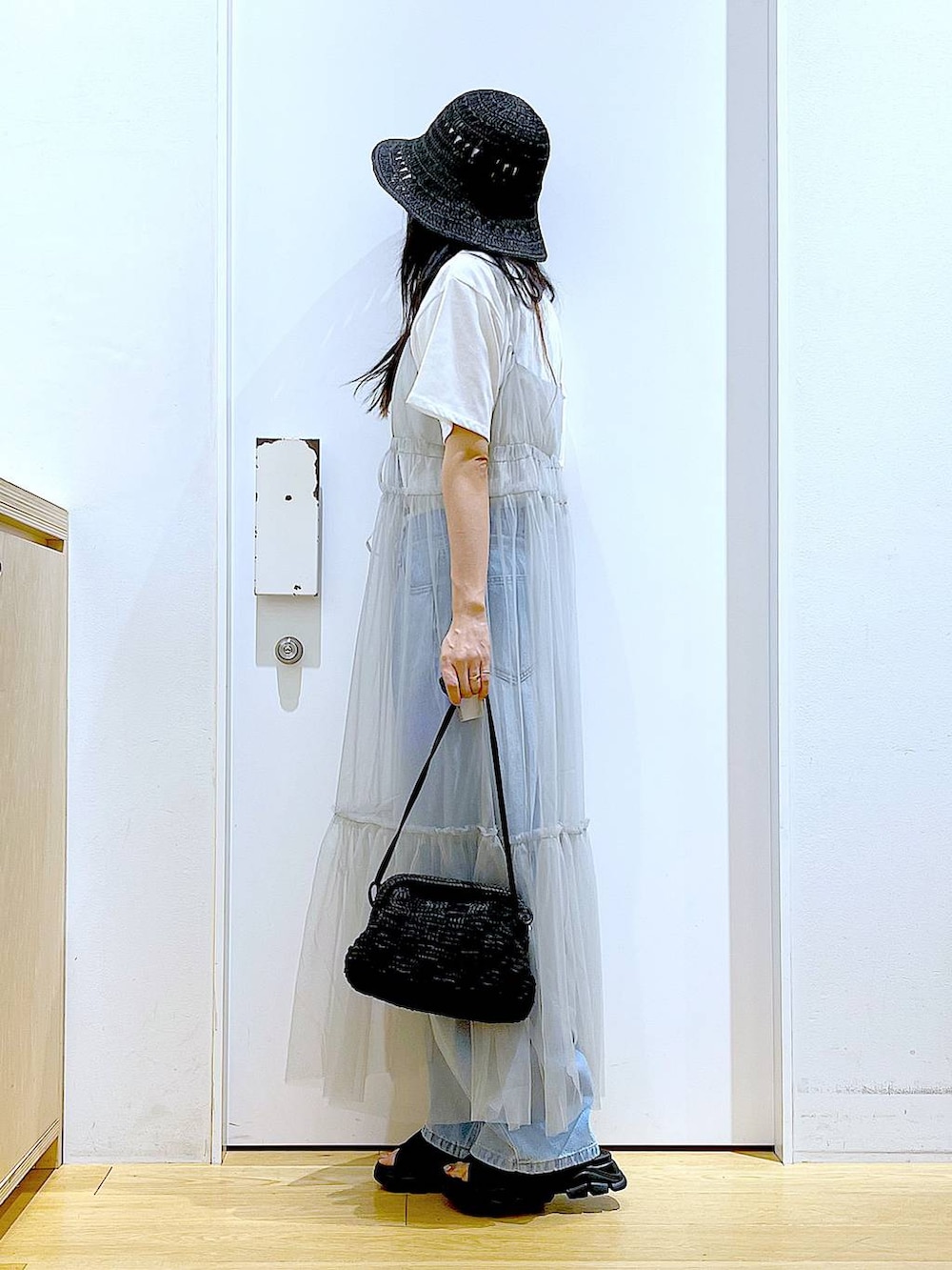 グレー系のワンピース、ブルー系のデニムパンツ、ブラック系のショルダーバッグを着用したレディースの夏コーディネートの3枚目の写真
