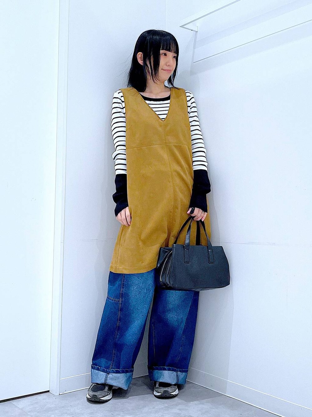 ブラック系のボストンバッグ、ホワイト系のニット/セーター、イエロー系のワンピースを着用したレディースの春コーディネートの2枚目の写真