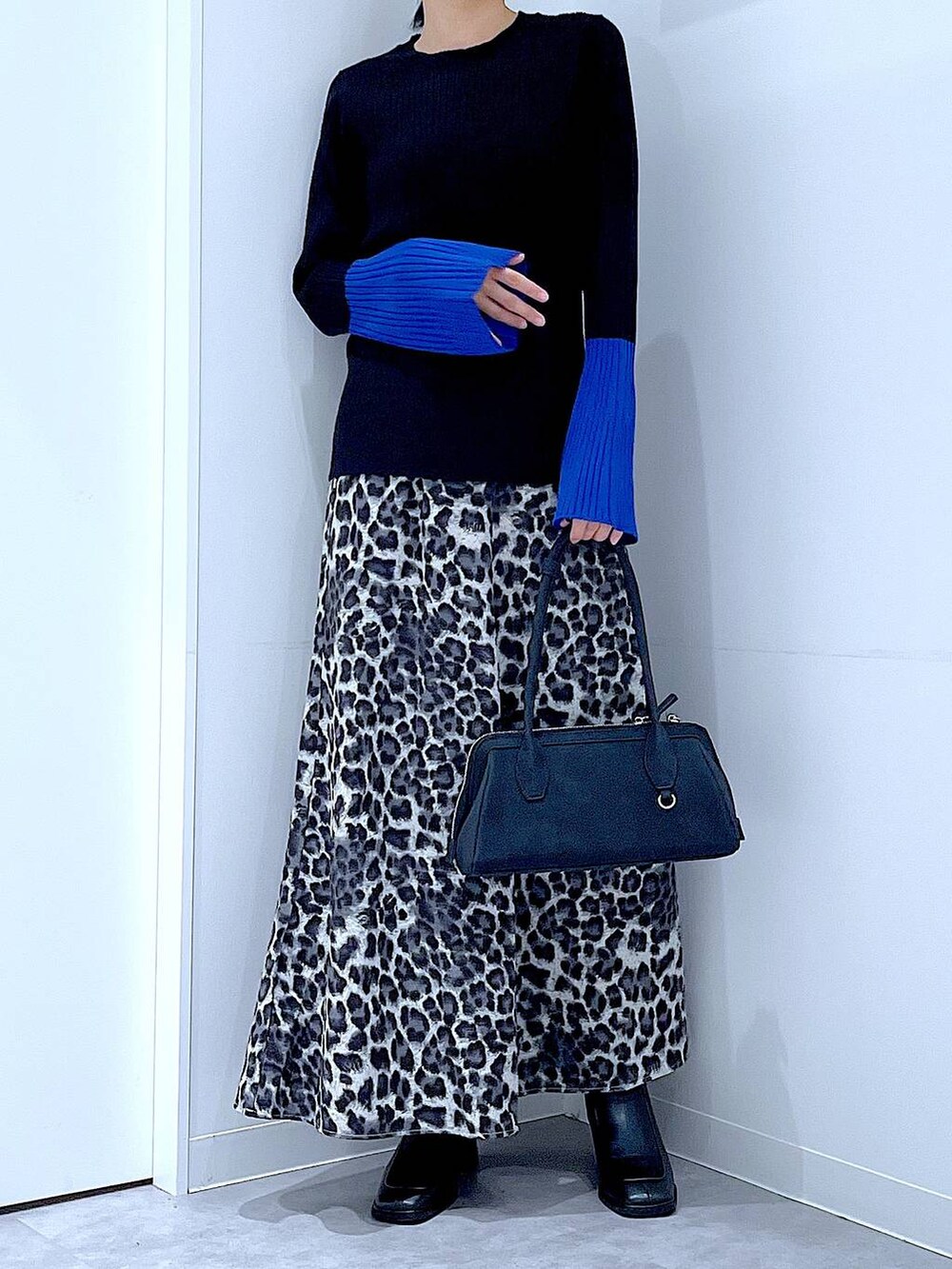 ブラック系のニット/セーター、ブラック系のブーツ、グレー系のスカートを着用したレディースの秋コーディネートの6枚目の写真