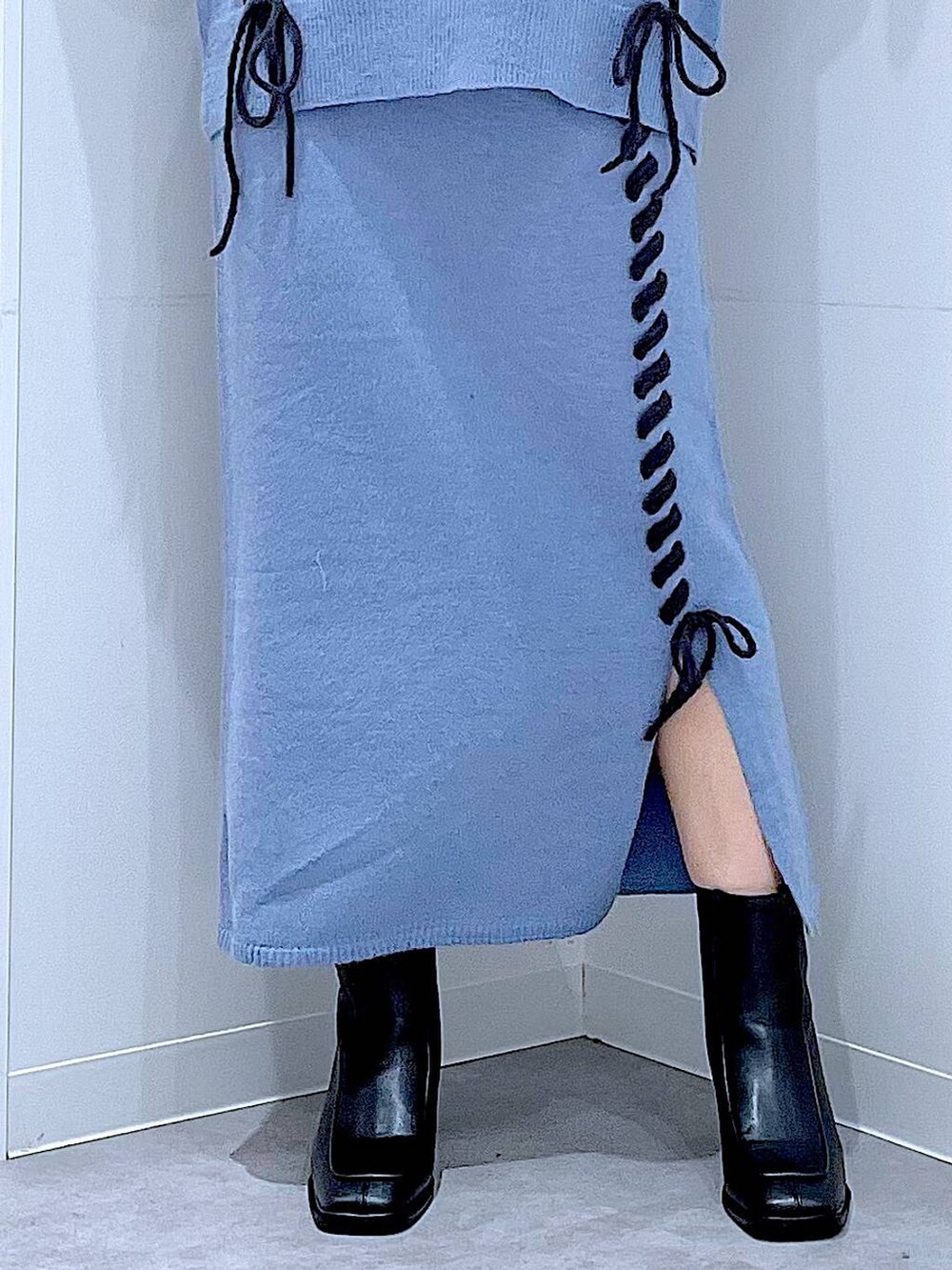 ブルー系のニット/セーター、ブルー系のスカート、ブラック系のブーツを着用したレディースの秋コーディネートの8枚目の写真