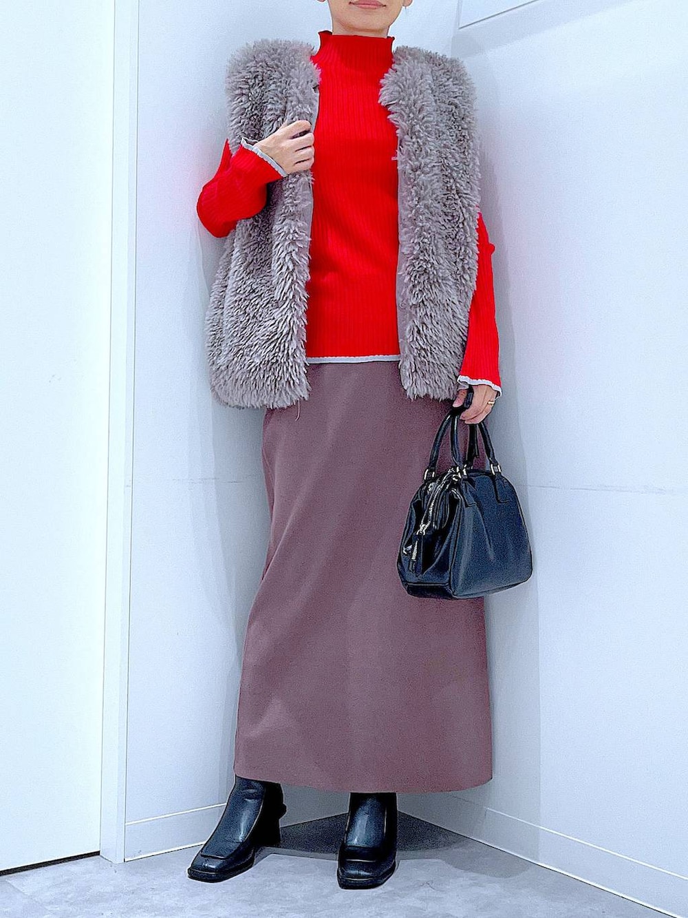 グレー系のベスト、レッド系のニット/セーター、ブラック系のブーツを着用したレディースの冬コーディネートの6枚目の写真