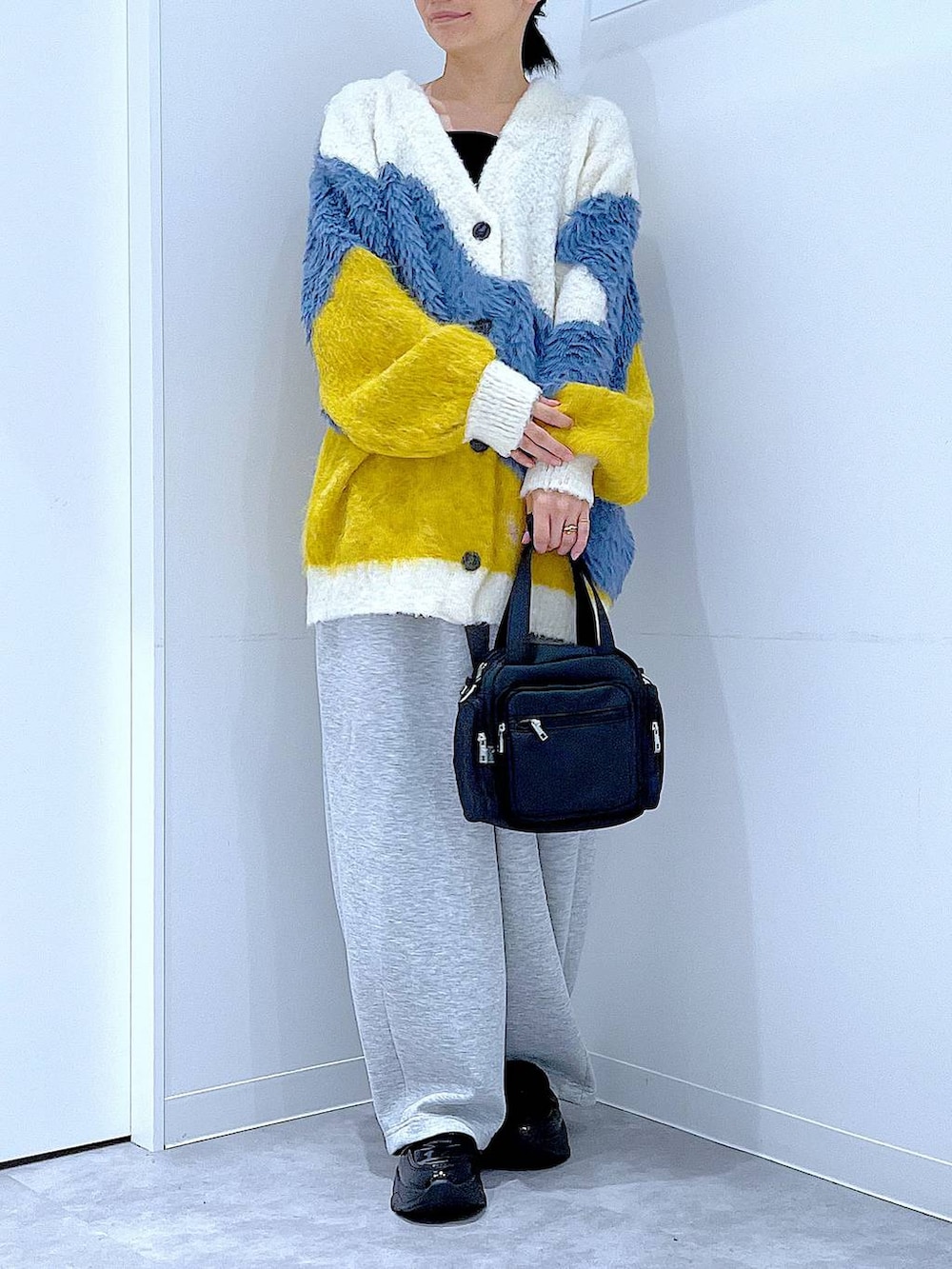 ブラック系のショルダーバッグ、ブラック系のローファー、イエロー系のカーディガン/ボレロを着用したレディースの秋コーディネートの6枚目の写真