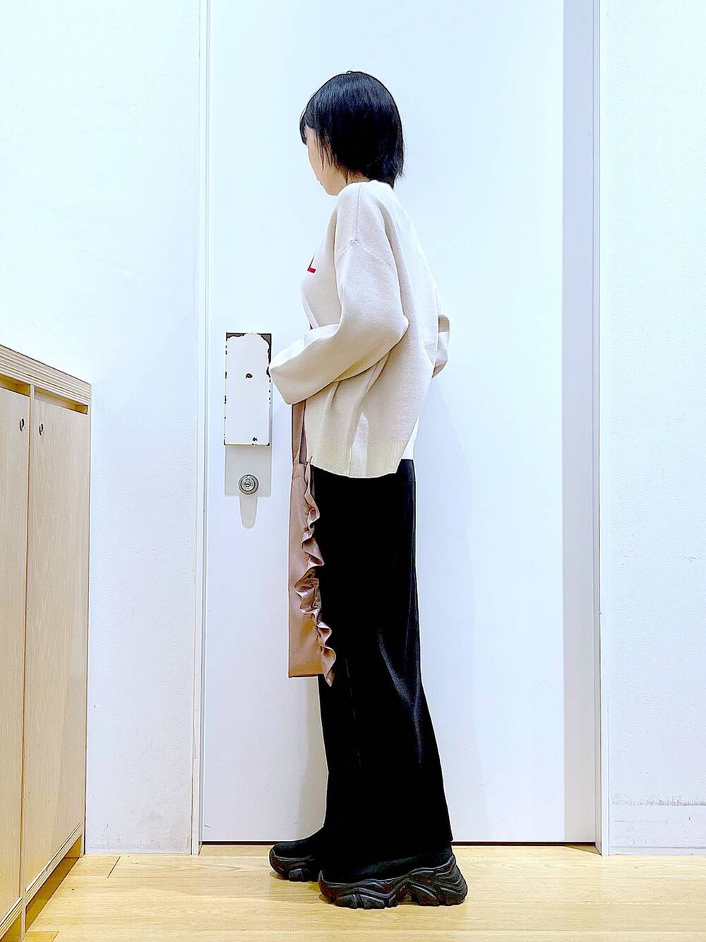 ブラック系のブーツ、ブラック系のスカート、ピンク系のトートバッグを着用したレディースの冬コーディネートの3枚目の写真