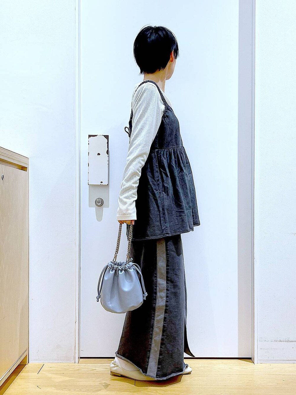 ブルー系のショルダーバッグ、ホワイト系のパンプス、ブラック系のデニムスカートを着用したレディースの春コーディネートの4枚目の写真