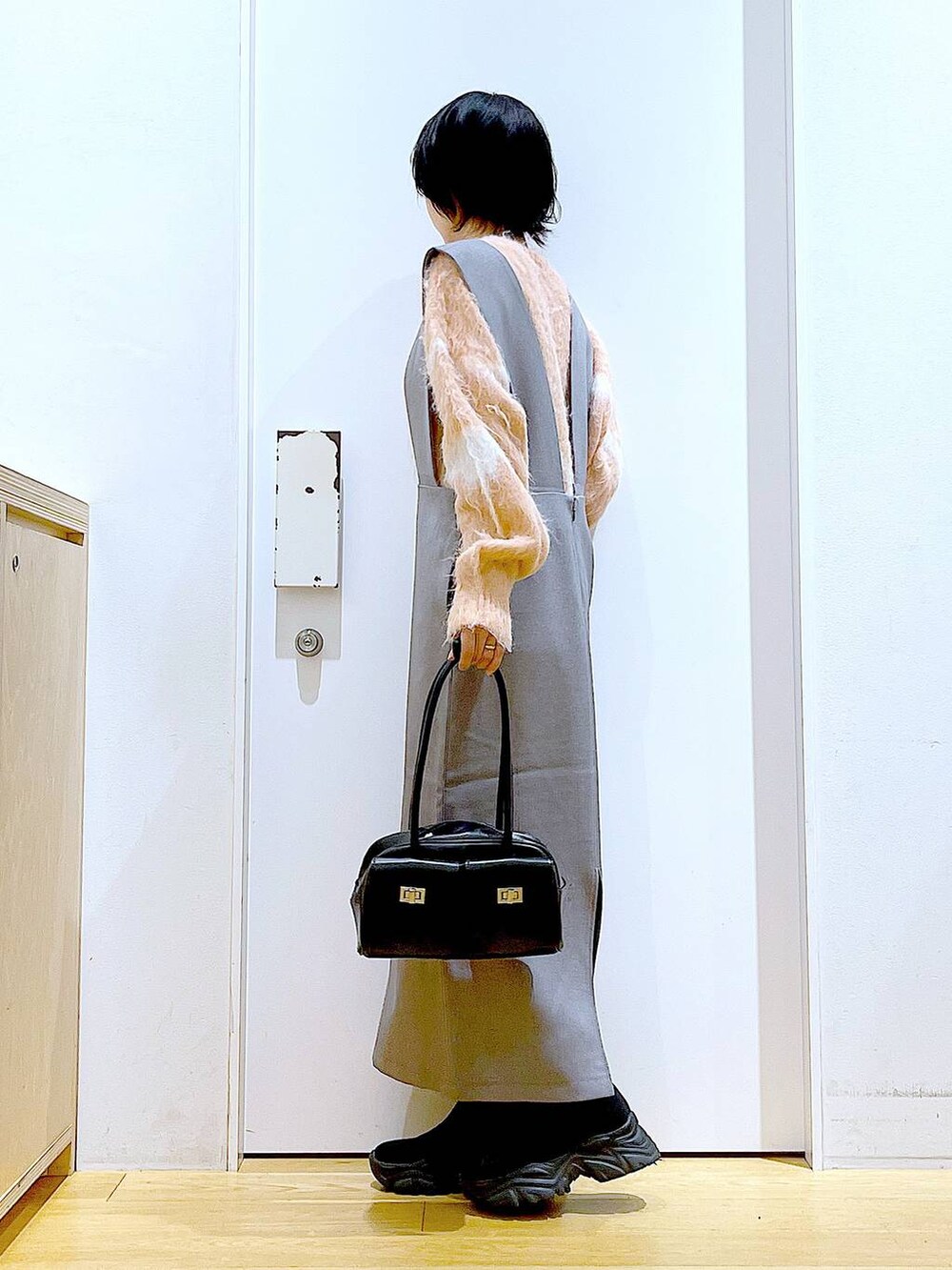 ピンク系のニット/セーター、ブラック系のハンドバッグ、ブラック系のブーツを着用したレディースの冬コーディネートの3枚目の写真