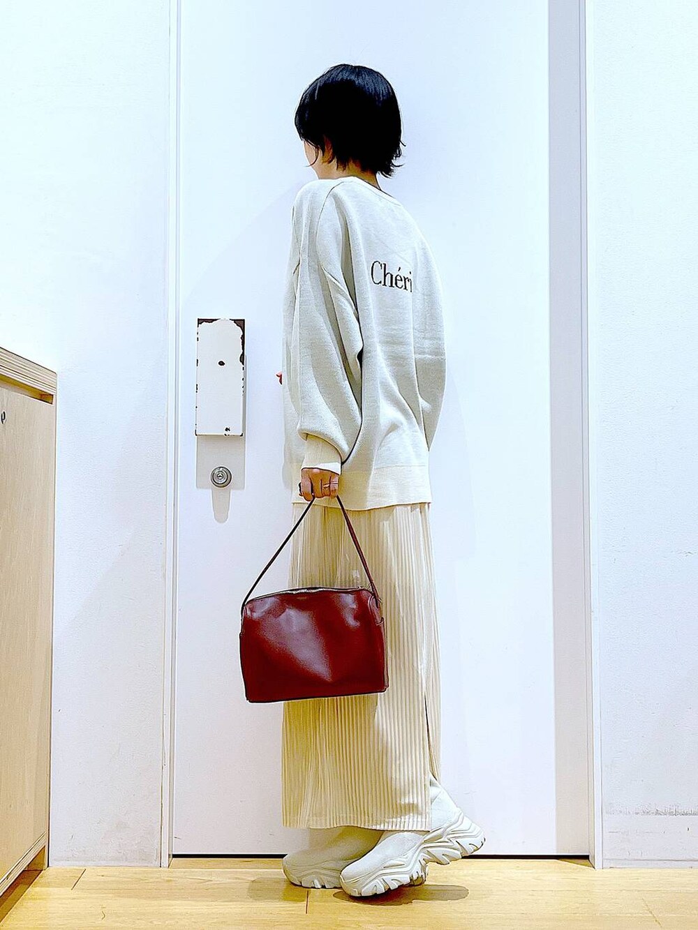 ベージュ系のニット/セーター、レッド系のショルダーバッグ、ベージュ系のブーツを着用したレディースの冬コーディネートの3枚目の写真