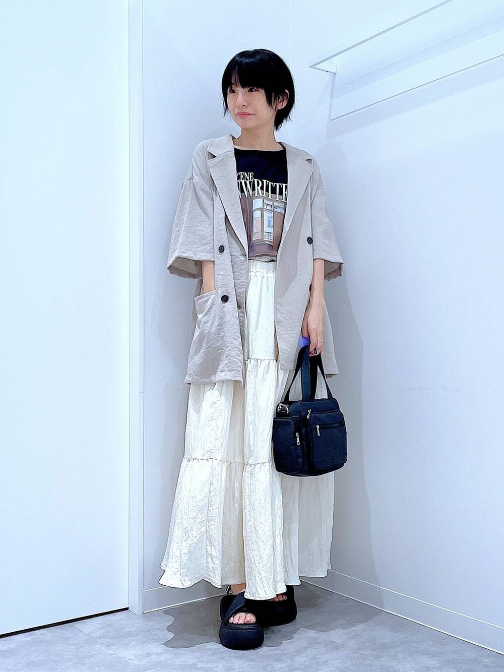 ブラック系のサンダル、ベージュ系のテーラードジャケット、ブラック系のショルダーバッグを着用したレディースの夏コーディネートの2枚目の写真