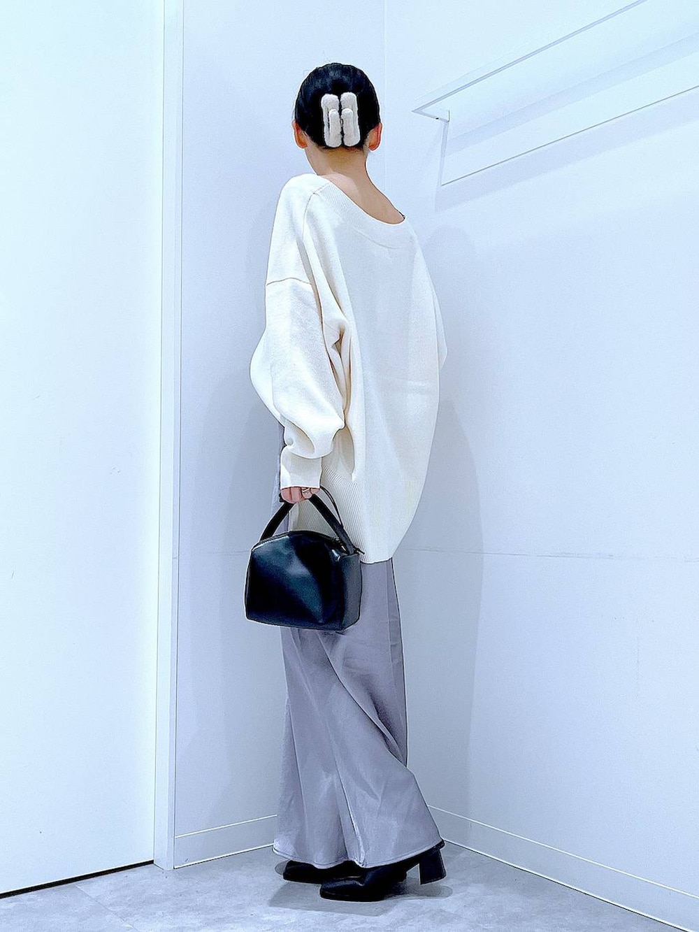 ベージュ系のニット/セーター、ブラック系のブーツ、ブラック系のショルダーバッグを着用したレディースの冬コーディネートの3枚目の写真