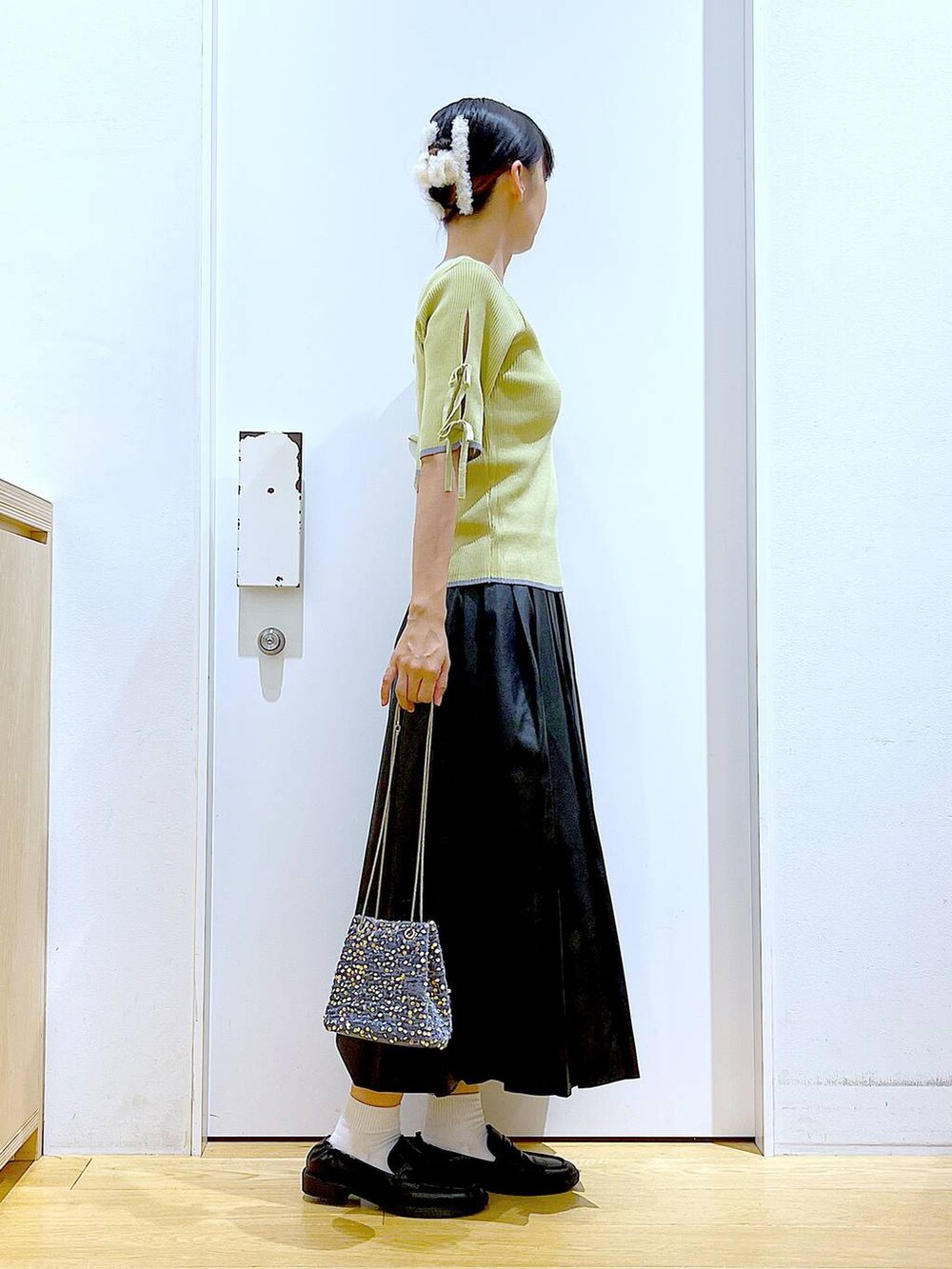 グレー系のショルダーバッグ、ブラック系のローファー、イエロー系のニット/セーターを着用したレディースの秋コーディネートの4枚目の写真