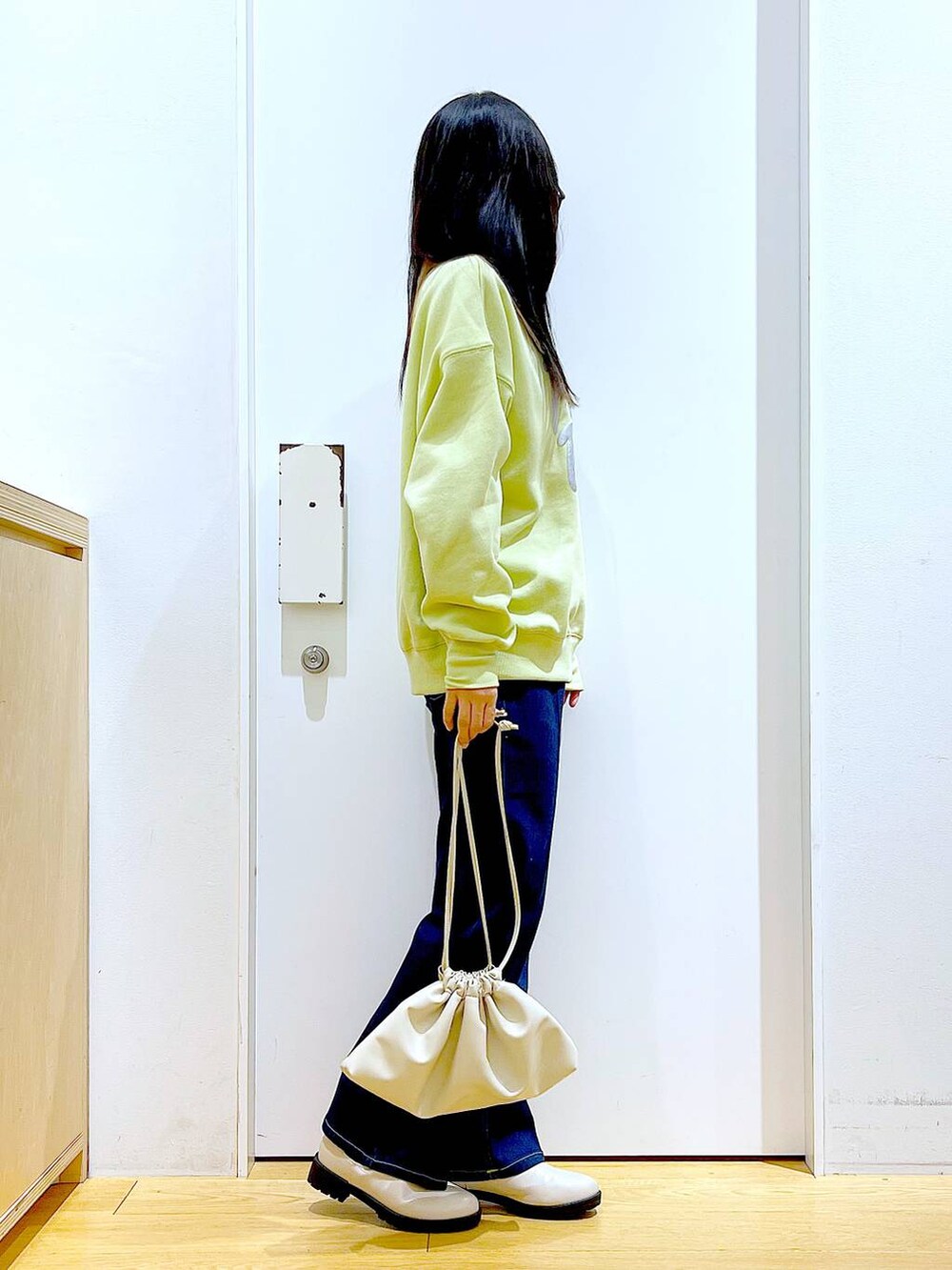 ブルー系のデニムパンツ、イエロー系のスウェット、ベージュ系のブーツを着用したレディースの冬コーディネートの4枚目の写真