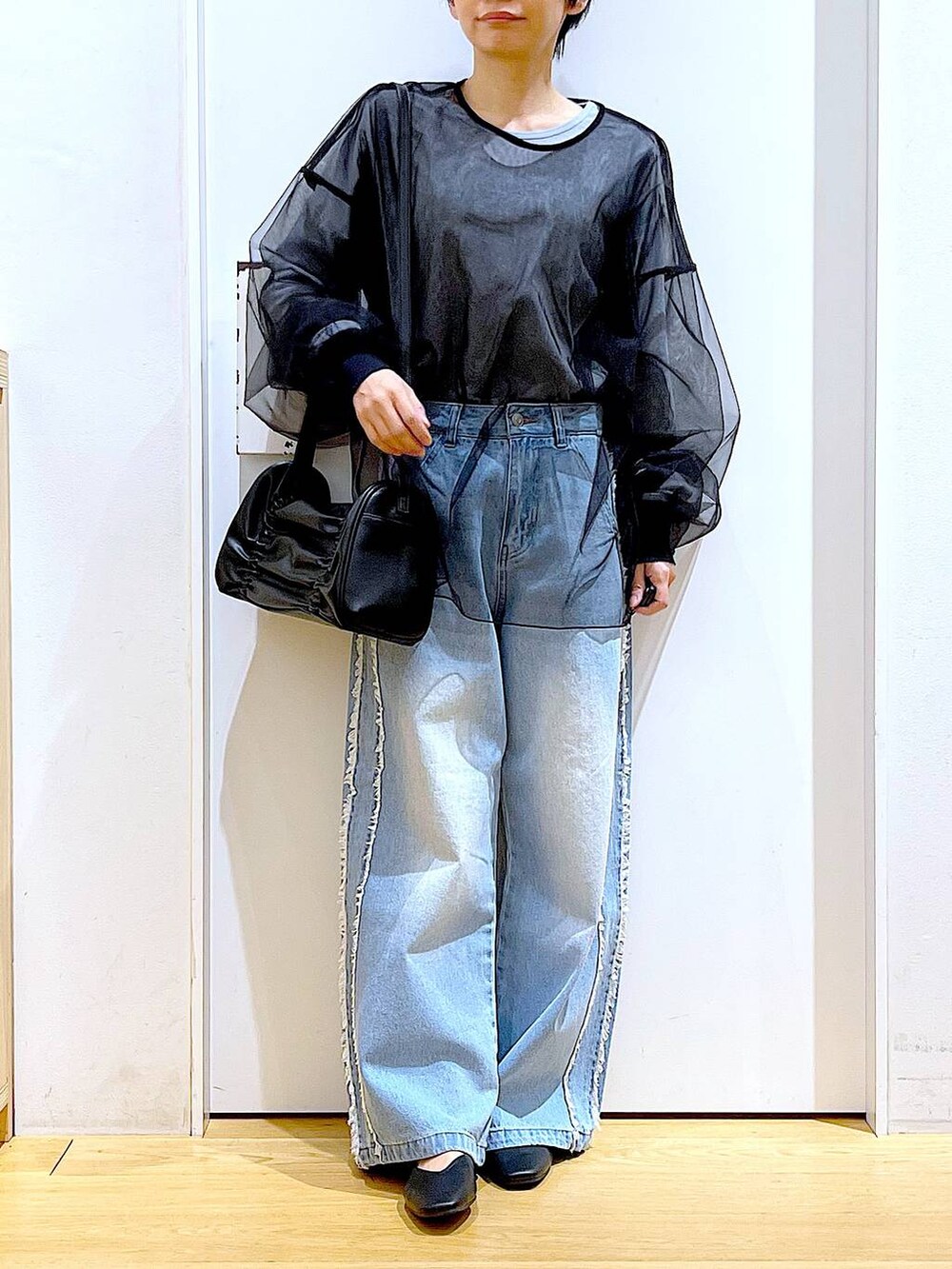 ブラック系のショルダーバッグ、ブラック系のパンプス、ブルー系のデニムパンツを着用したレディースの春コーディネートの6枚目の写真