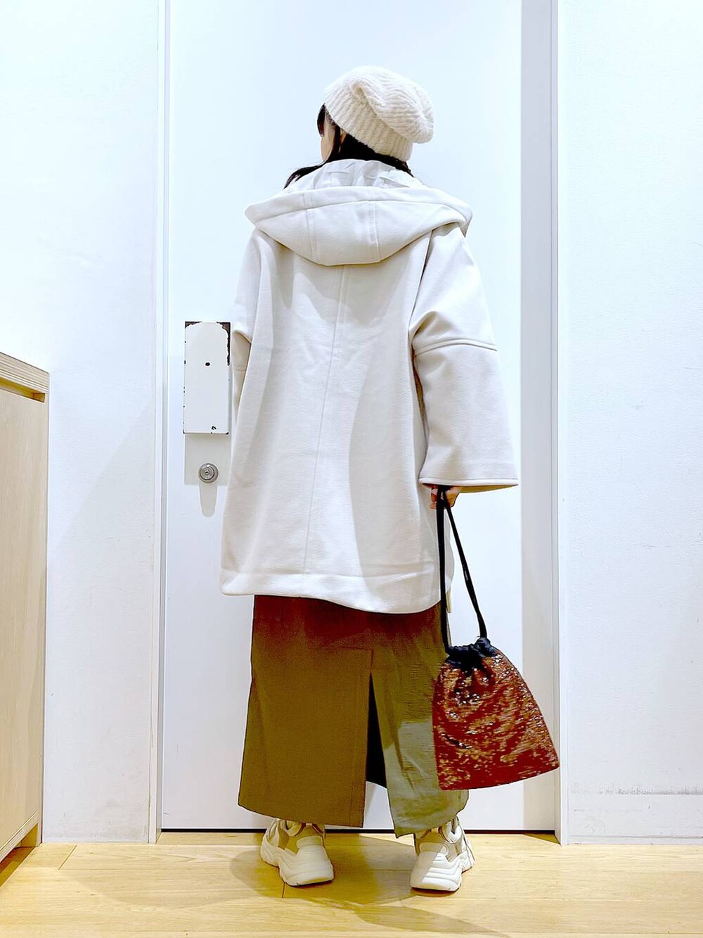 ホワイト系のその他アウター、ブラウン系のショルダーバッグ、ベージュ系のスニーカーを着用したレディースの冬コーディネートの5枚目の写真