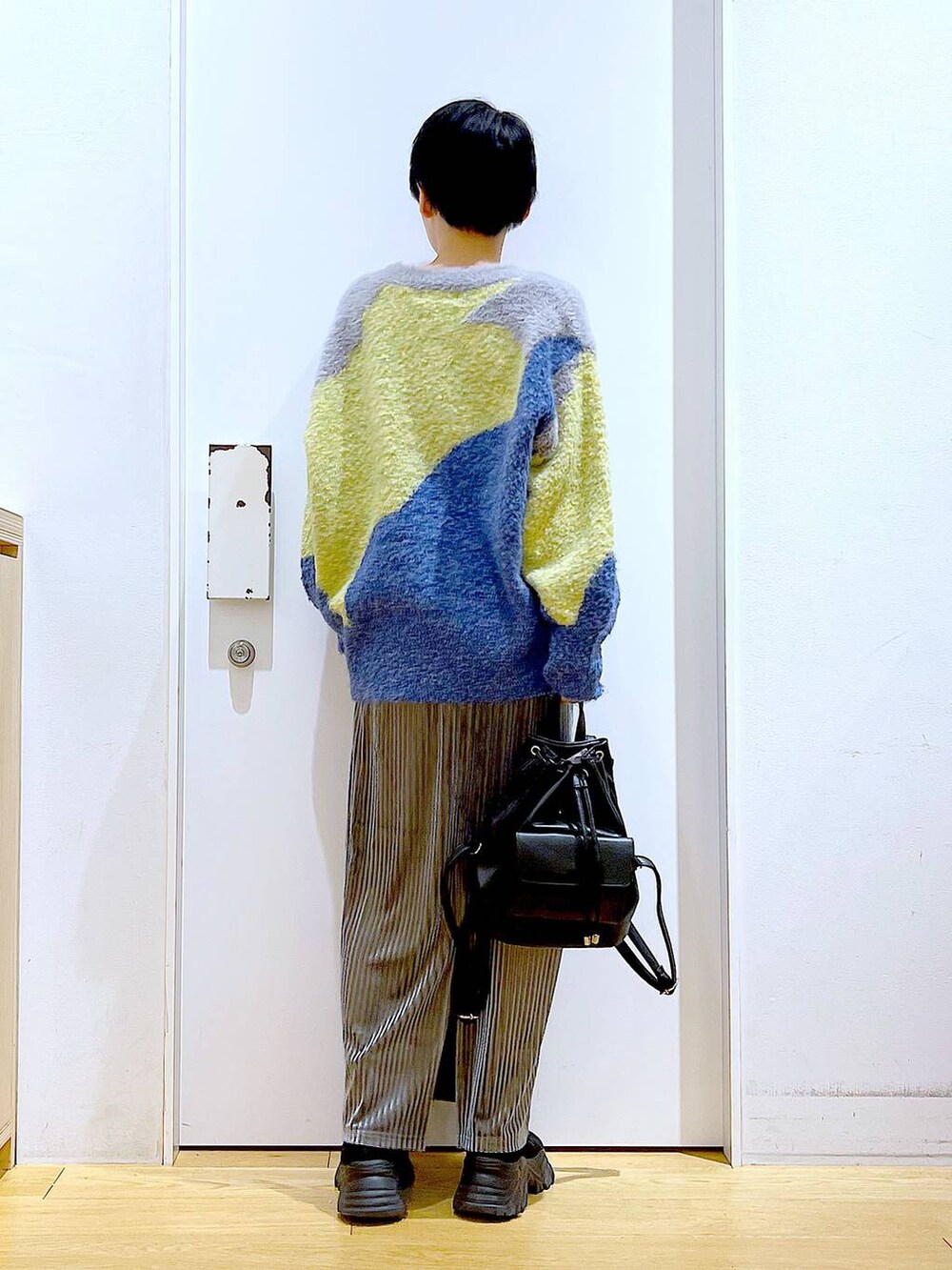 ブラック系のバックパック/リュック、グレー系のスカート、ブラック系のブーツを着用したレディースの冬コーディネートの5枚目の写真