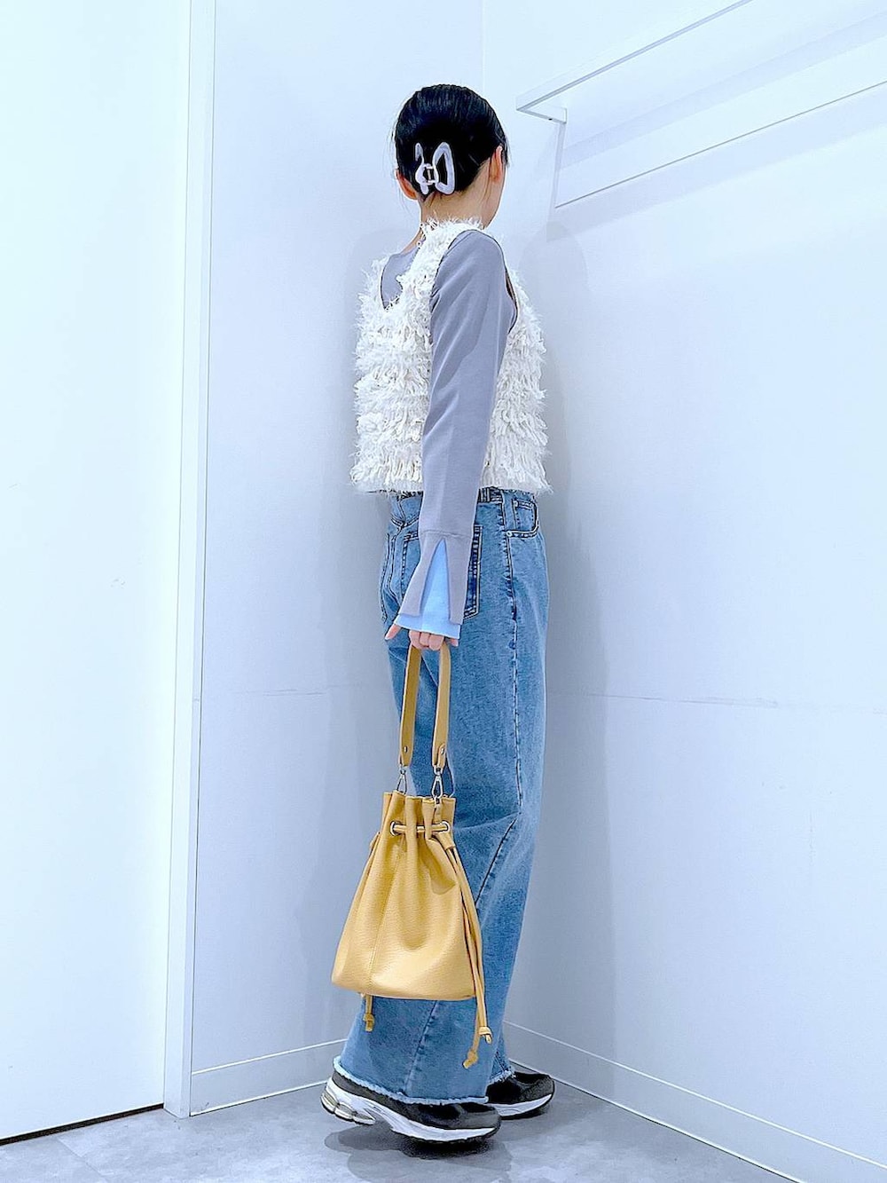 ホワイト系のベスト、グレー系のニット/セーター、ブルー系のデニムパンツを着用したレディースの春コーディネートの4枚目の写真