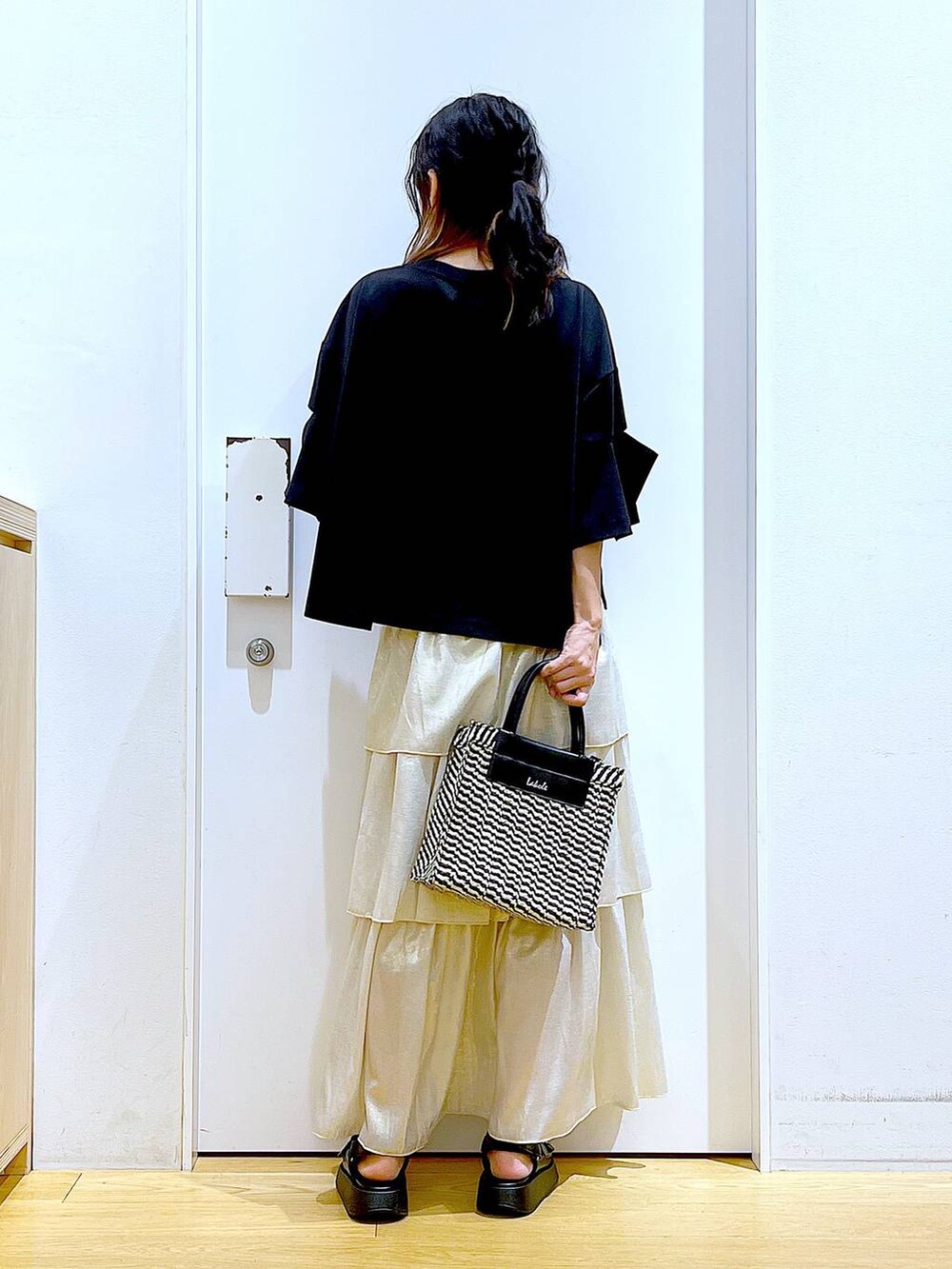 ブラック系のサンダル、ブラック系のショルダーバッグ、ゴールド系のスカートを着用したレディースの夏コーディネートの5枚目の写真