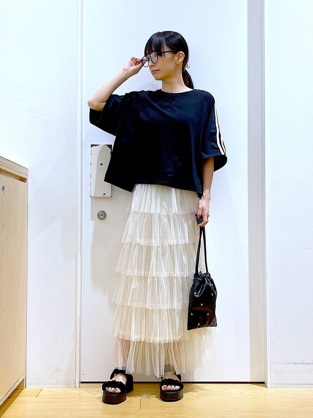 ブラック系のサンダル、ブラック系のショルダーバッグ、ベージュ系のスカートを着用したレディースの夏コーディネートの2枚目の写真