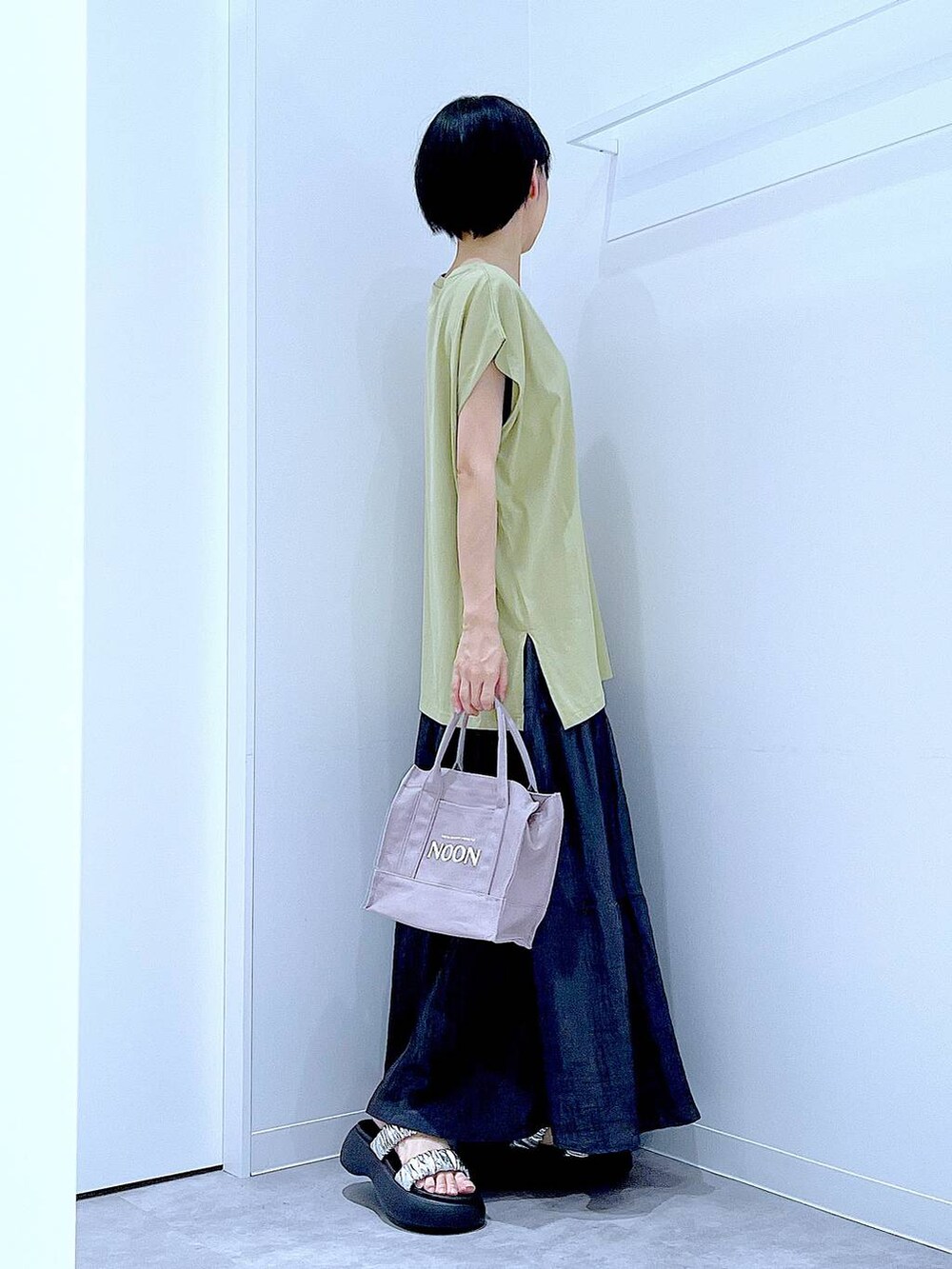 シルバー系のサンダル、グリーン系のTシャツ/カットソー、ブラック系のスカートを着用したレディースの夏コーディネートの4枚目の写真