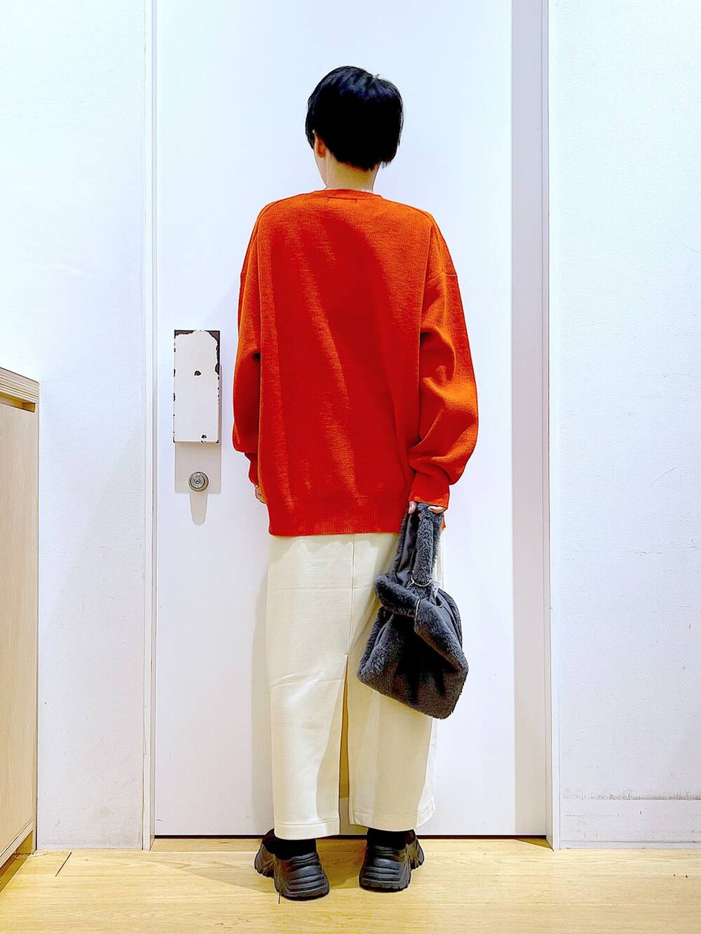 グレー系のショルダーバッグ、オレンジ系のニット/セーター、ブラック系のブーツを着用したレディースの冬コーディネートの5枚目の写真