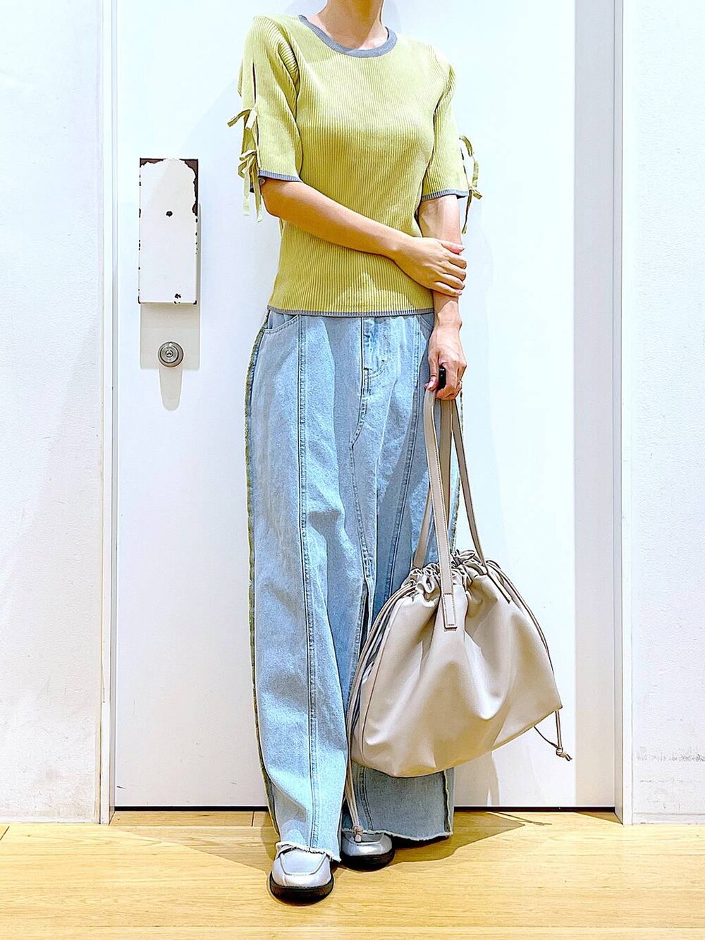 ベージュ系のトートバッグ、シルバー系のローファー、イエロー系のニット/セーターを着用したレディースの秋コーディネートの6枚目の写真