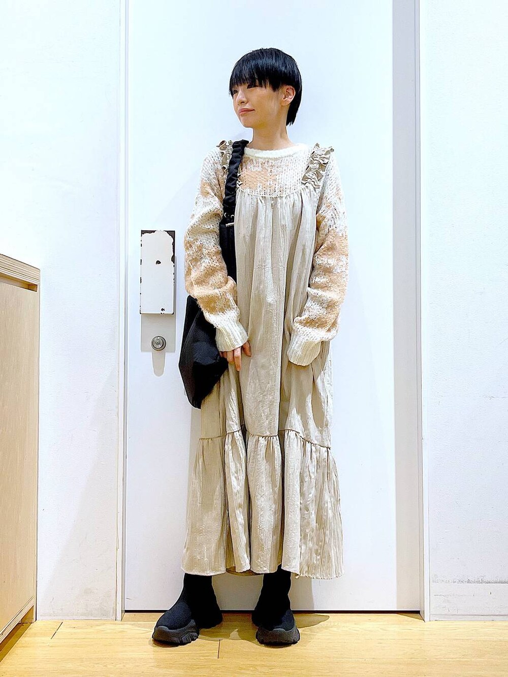 ブラック系のショルダーバッグ、ブラック系のブーツ、ベージュ系のワンピースを着用したレディースの冬コーディネートの2枚目の写真