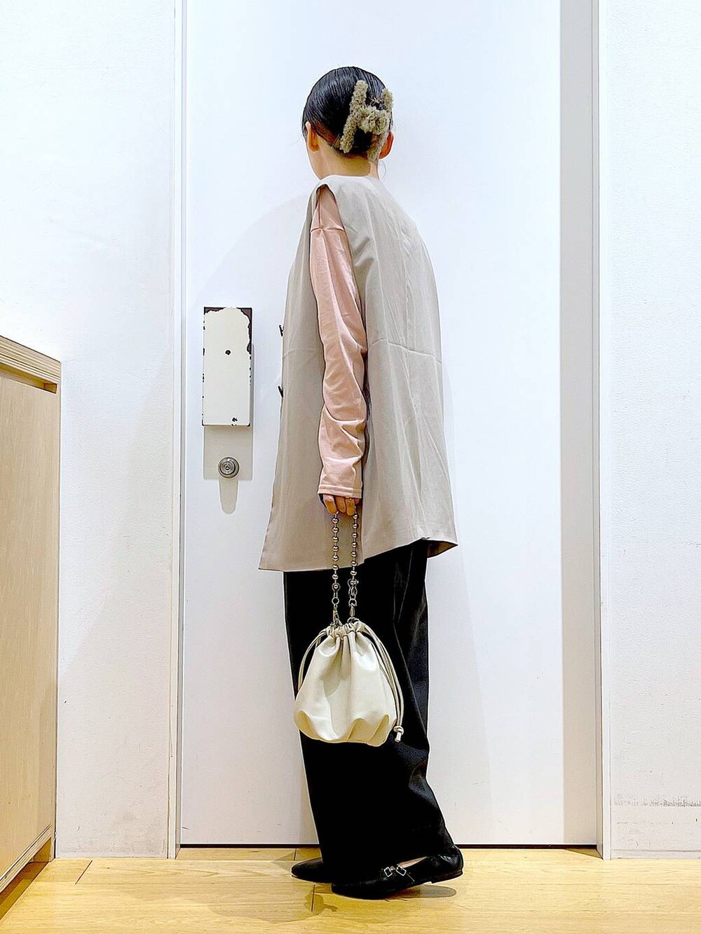 ベージュ系のショルダーバッグ、ブラック系のパンプス、ベージュ系のベストを着用したレディースの秋コーディネートの3枚目の写真