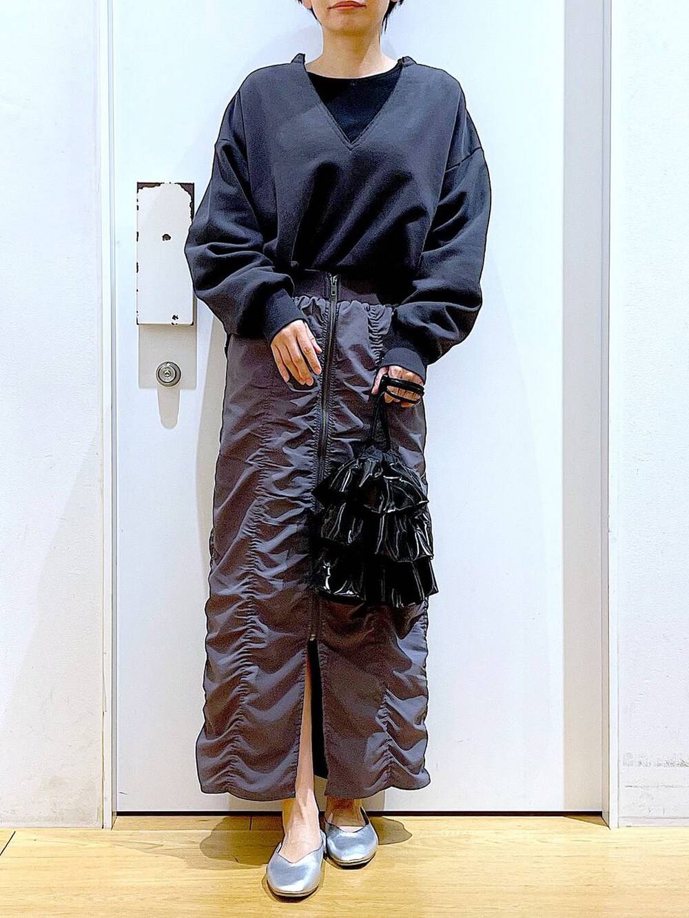 グレー系のスカート、ブラック系のショルダーバッグ、シルバー系のパンプスを着用したレディースの春コーディネートの6枚目の写真