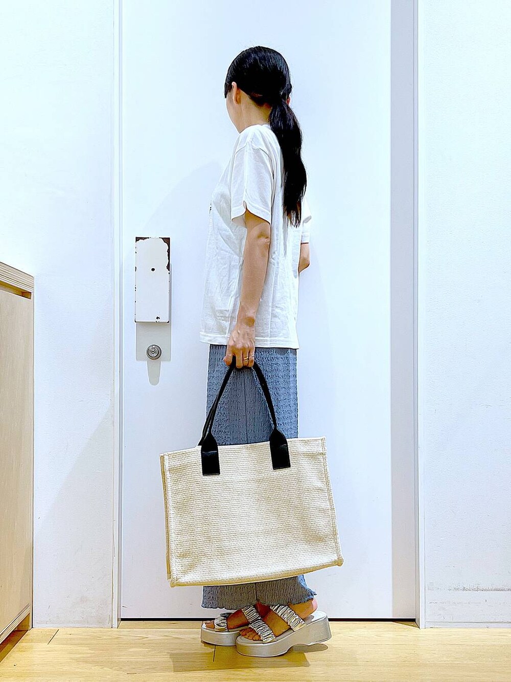 シルバー系のサンダル、ブルー系のスカート、ホワイト系のトートバッグを着用したレディースの夏コーディネートの3枚目の写真