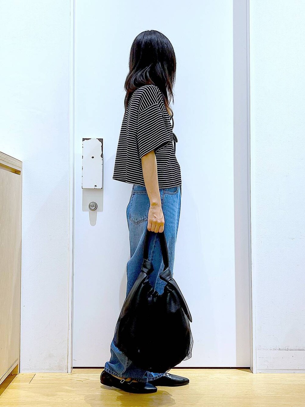 ブラック系のトートバッグ、ブルー系のデニムパンツ、その他のカーディガン/ボレロを着用したレディースの秋コーディネートの4枚目の写真