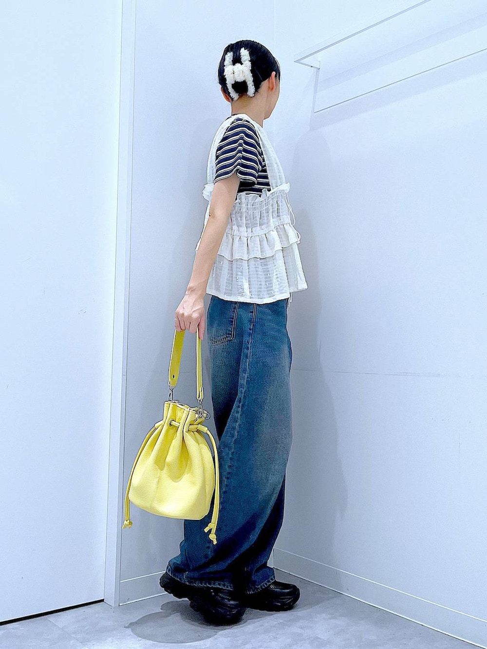 ブルー系のデニムパンツ、イエロー系のショルダーバッグ、ブラック系のスニーカーを着用したレディースの春コーディネートの4枚目の写真