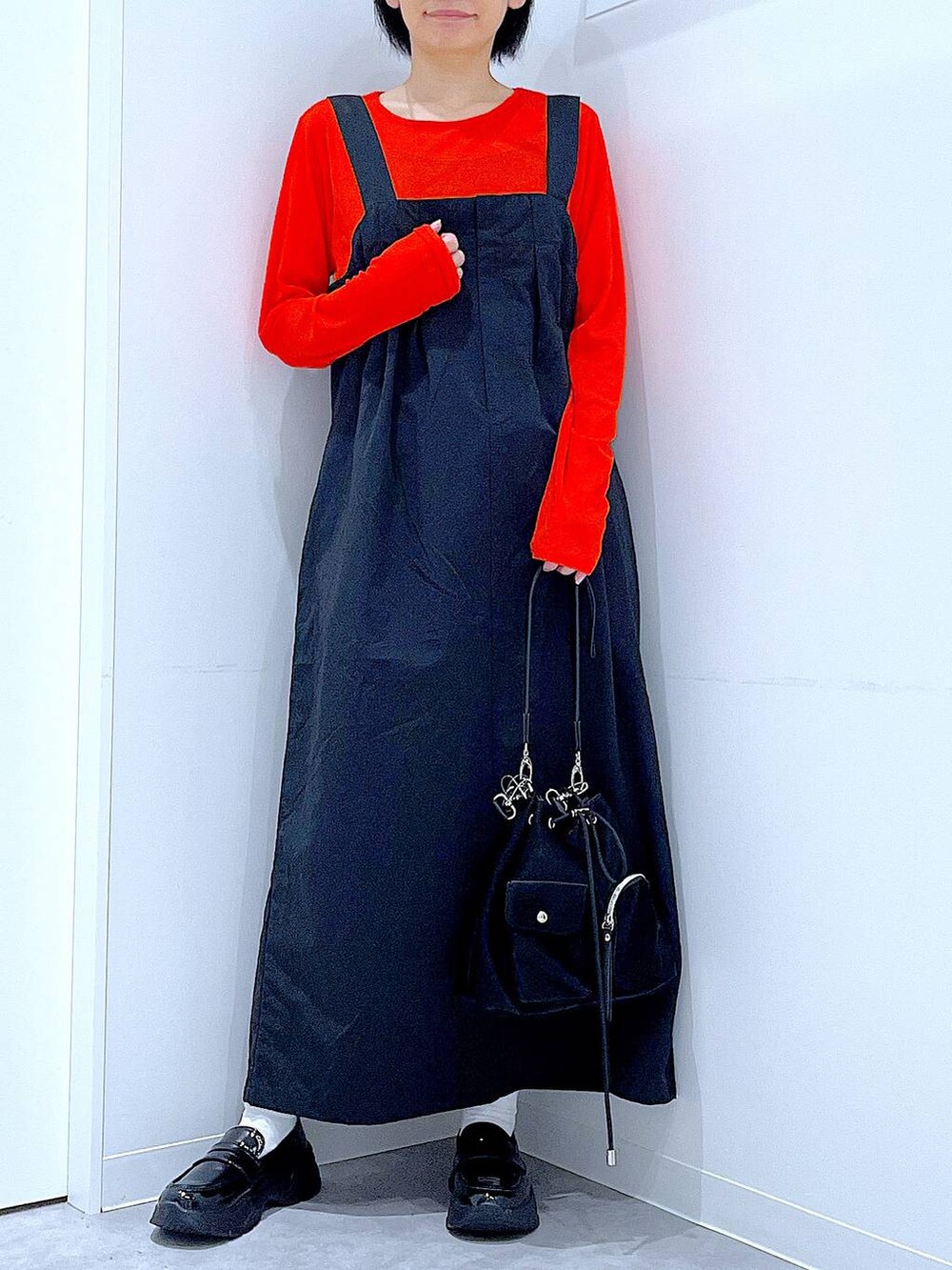 オレンジ系のTシャツ/カットソー、ブラック系のローファー、ブラック系のショルダーバッグを着用したレディースの秋コーディネートの6枚目の写真