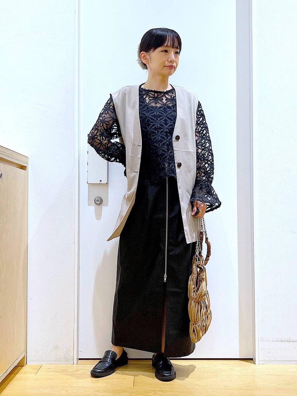 ブラック系のスカート、ブラック系のローファー、ベージュ系のベストを着用したレディースの秋コーディネートの2枚目の写真