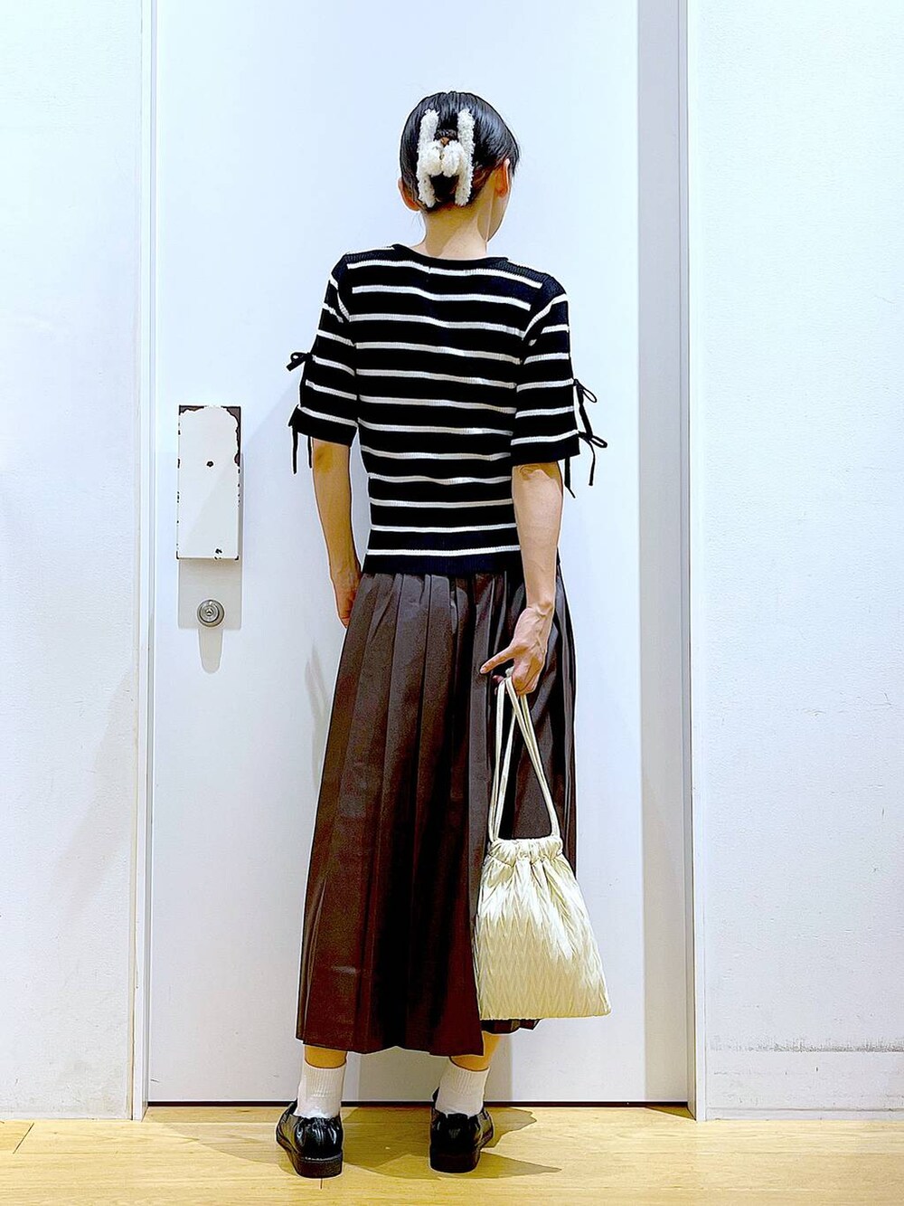 ホワイト系のショルダーバッグ、ブラック系のローファー、ブラック系のニット/セーターを着用したレディースの秋コーディネートの5枚目の写真