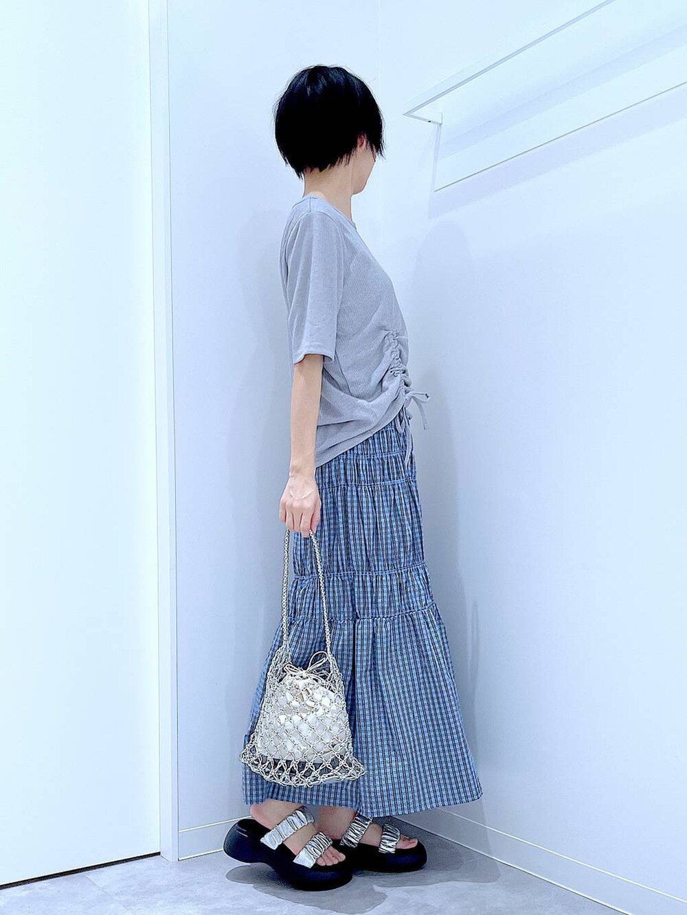 シルバー系のかごバッグ、シルバー系のサンダル、ブルー系のスカートを着用したレディースの夏コーディネートの4枚目の写真