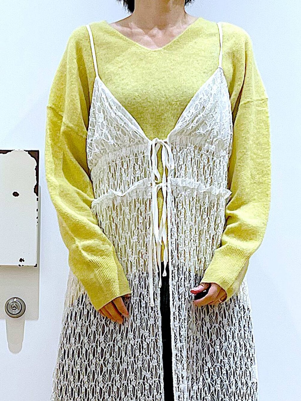 イエロー系のニット/セーター、グレー系のショルダーバッグ、ホワイト系のワンピースを着用したレディースの冬コーディネートの7枚目の写真