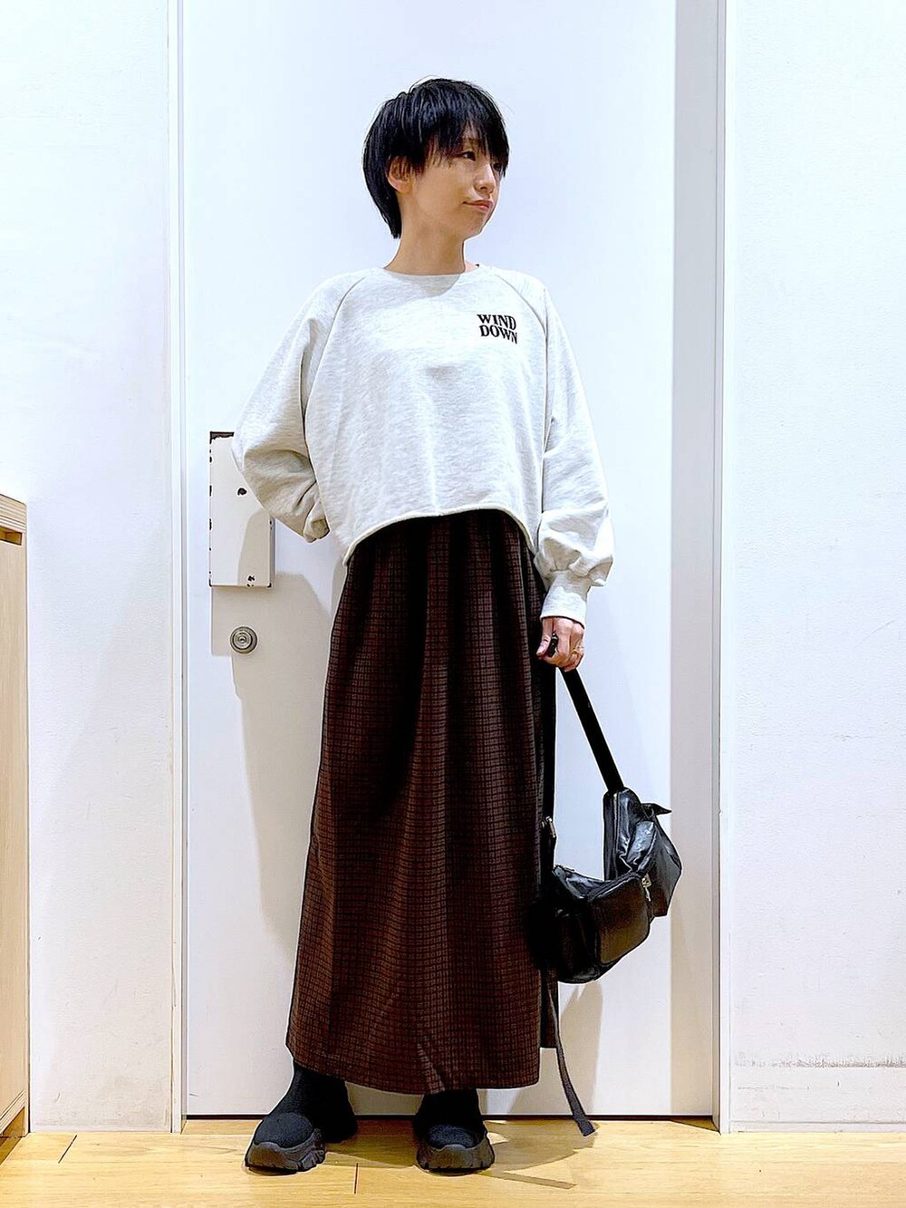 ブラック系のブーツ、ブラック系のショルダーバッグ、ブラウン系のワンピースを着用したレディースの冬コーディネートの2枚目の写真