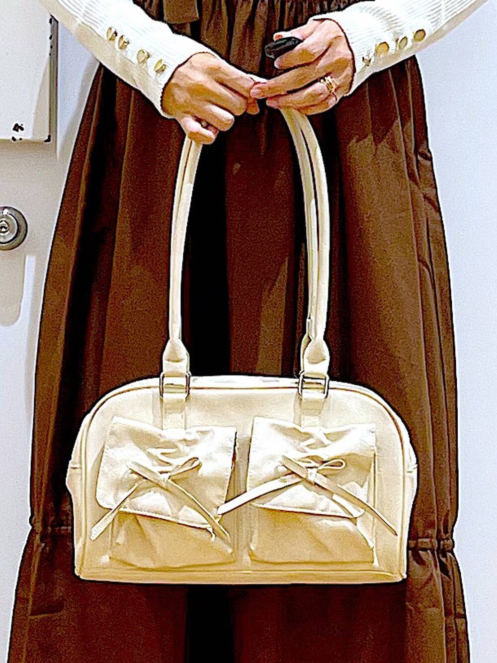 ホワイト系のニット/セーター、ホワイト系のハンドバッグ、ベージュ系のスリッポンを着用したレディースの冬コーディネートの9枚目の写真