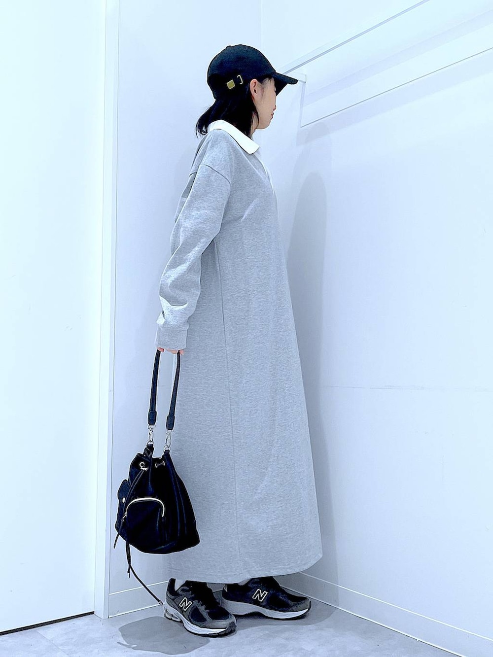 ブラック系のショルダーバッグ、グレー系のワンピース、ブラック系のキャップを着用したレディースの春コーディネートの4枚目の写真