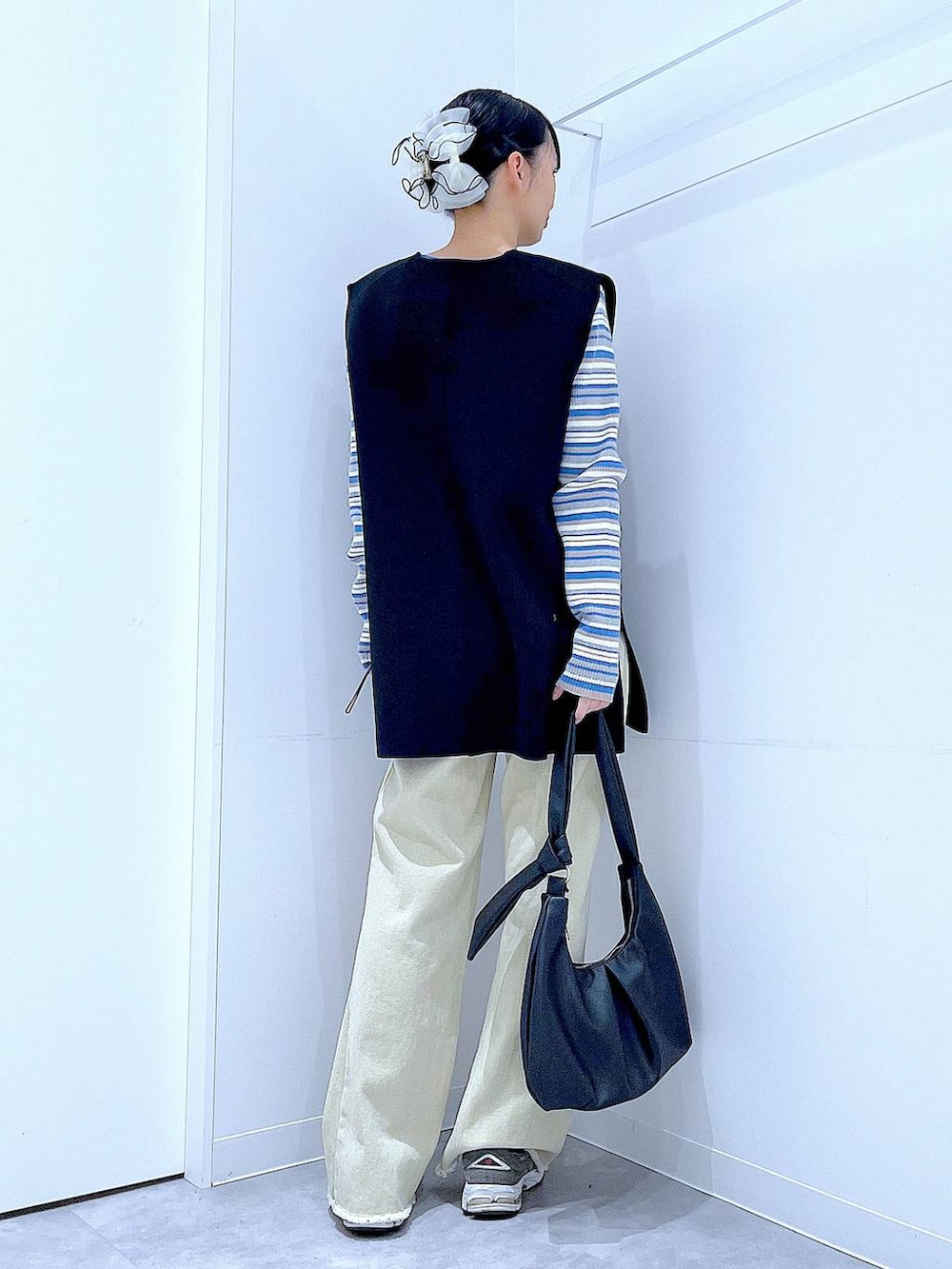 ブルー系のニット/セーター、ブラック系のベスト、ベージュ系のデニムパンツを着用したレディースの冬コーディネートの5枚目の写真