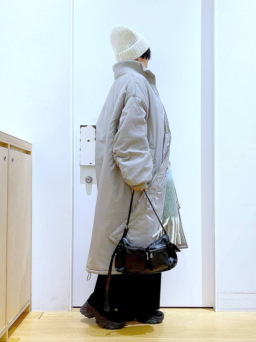 グレー系のミリタリージャケット、ブラック系のブーツ、ブラック系のショルダーバッグを着用したレディースの冬コーディネートの4枚目の写真