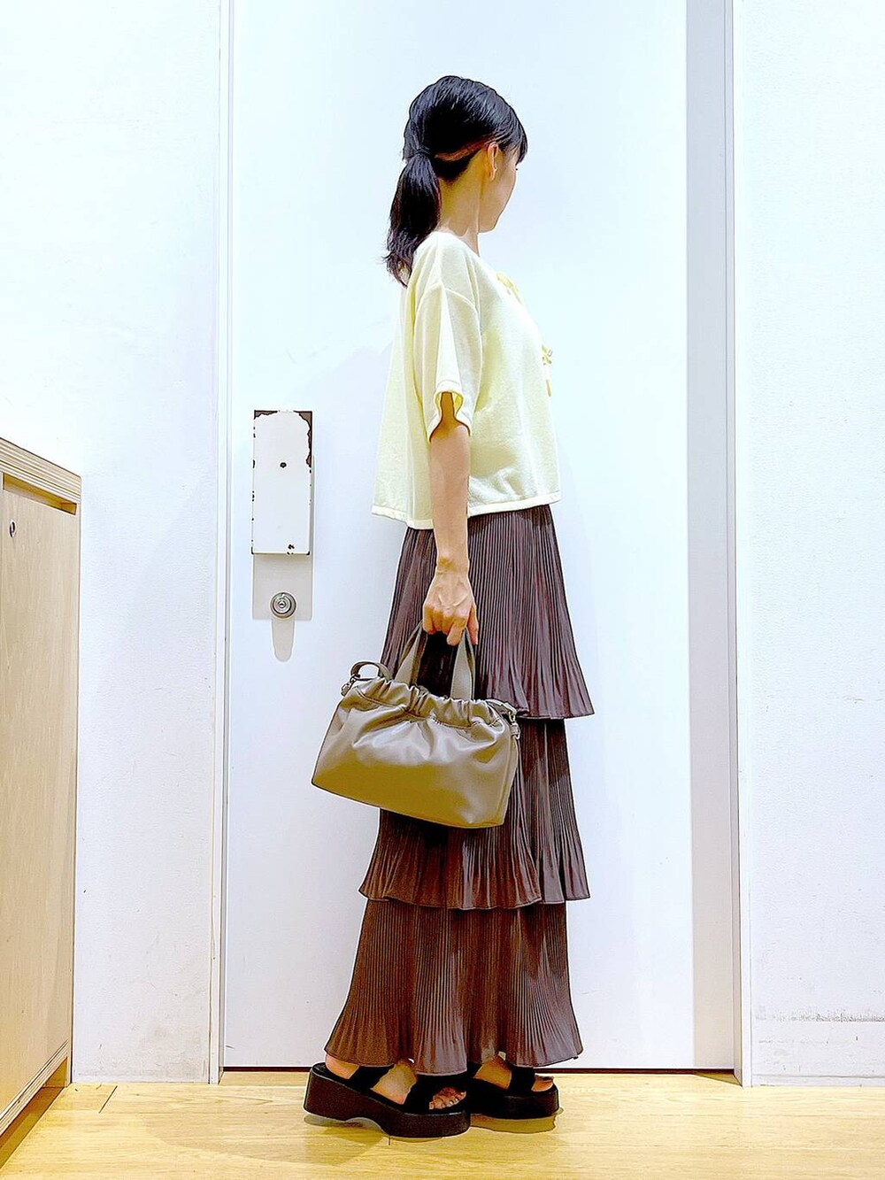 ブラウン系のスカート、ブラウン系のショルダーバッグ、ブラック系のサンダルを着用したレディースの秋コーディネートの4枚目の写真