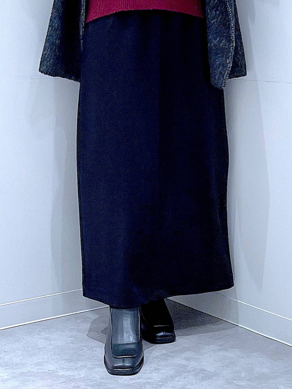 ブラック系のスカート、ブラック系のステンカラーコート、ブラック系のブーツを着用したレディースの冬コーディネートの8枚目の写真