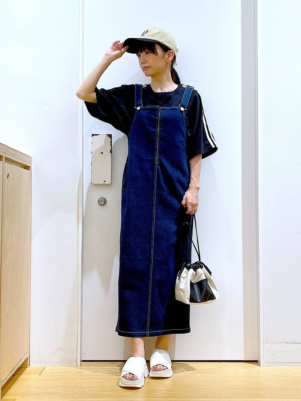 ブルー系のジャンパースカート、ホワイト系のショルダーバッグ、ホワイト系のサンダルを着用したレディースの夏コーディネートの2枚目の写真