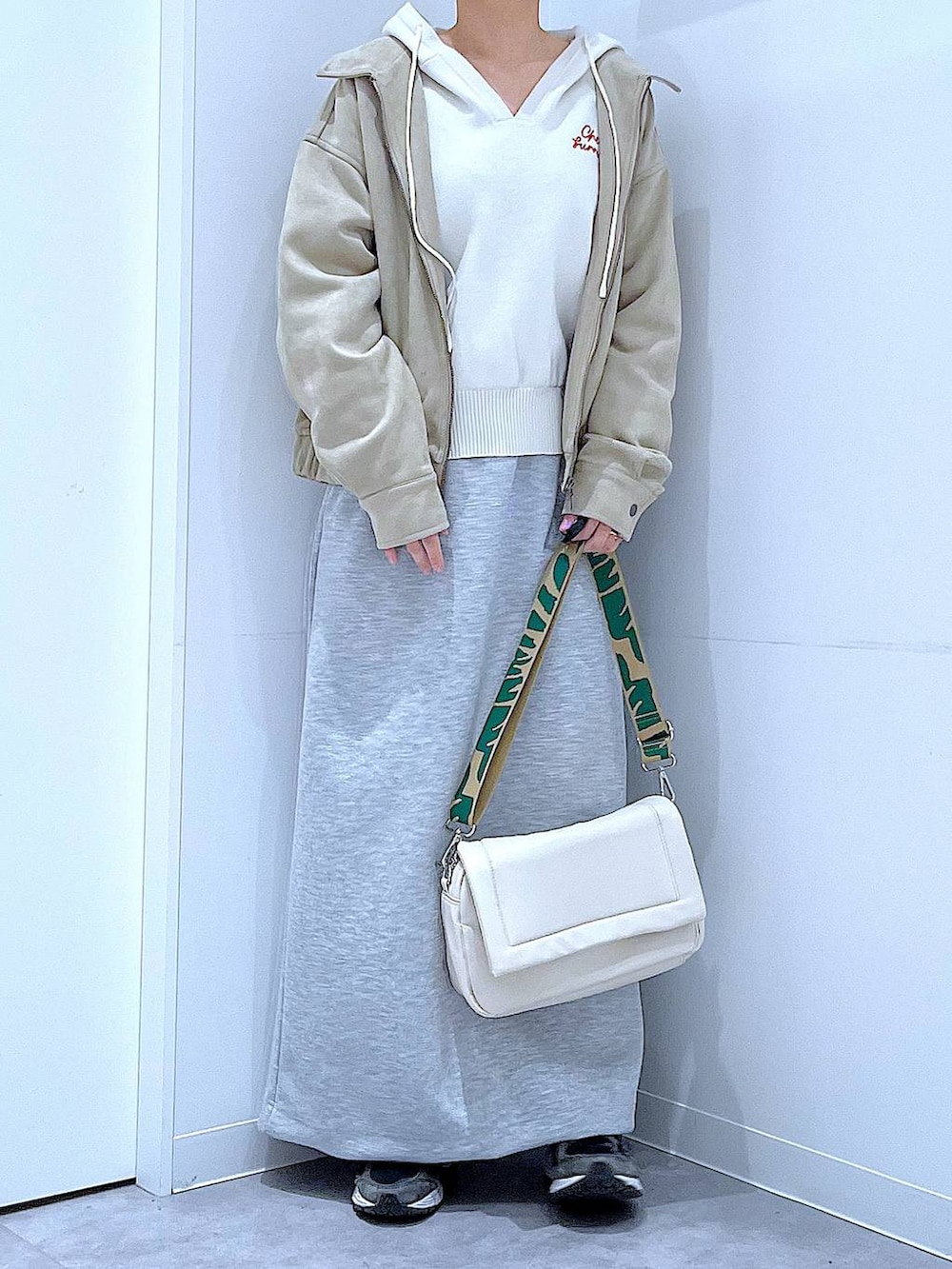 ホワイト系のショルダーバッグ、ベージュ系のニット/セーター、グレー系のスカートを着用したレディースの春コーディネートの6枚目の写真